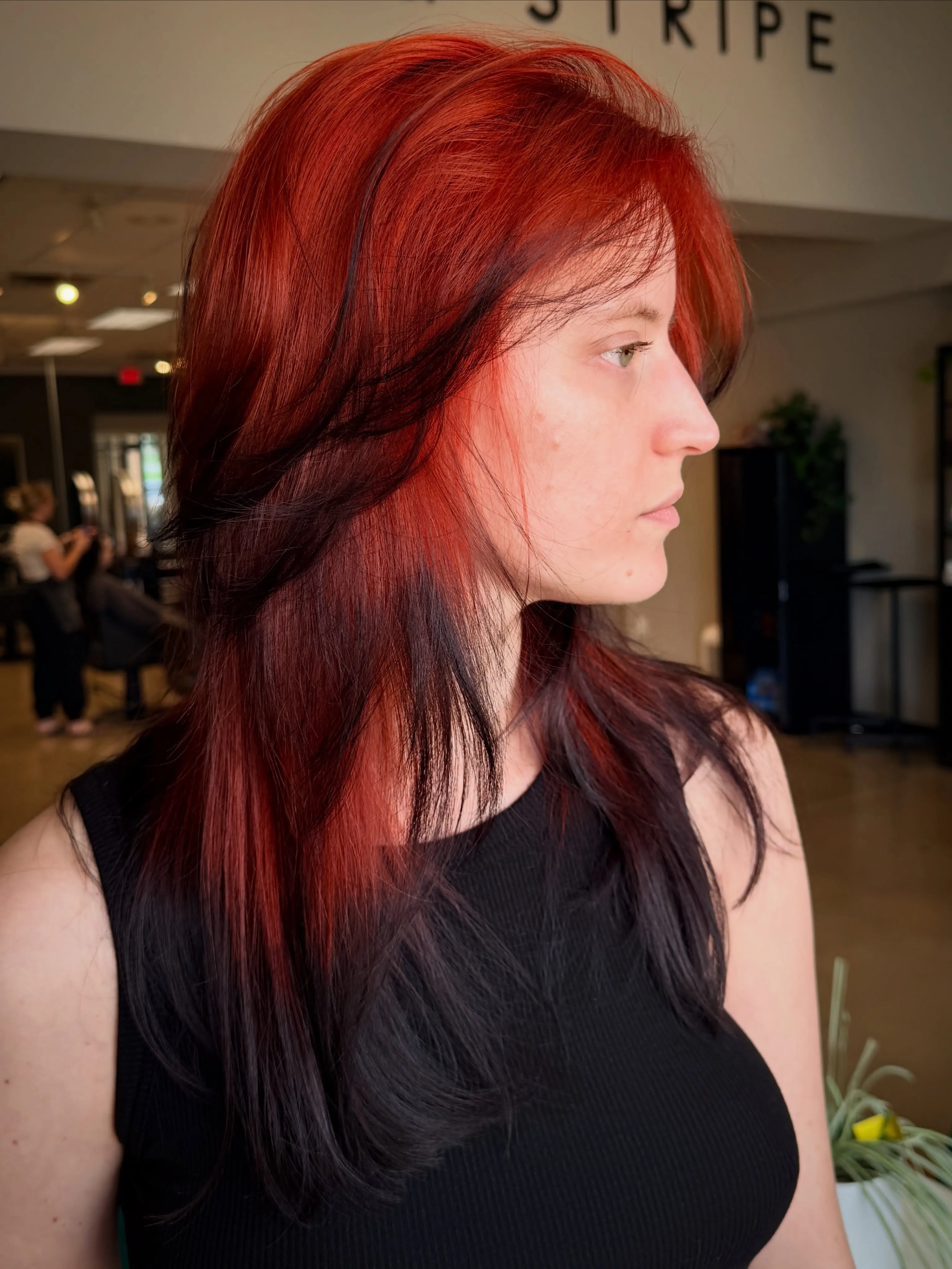 Long layered hair with bright red upper sections and dark underlayers