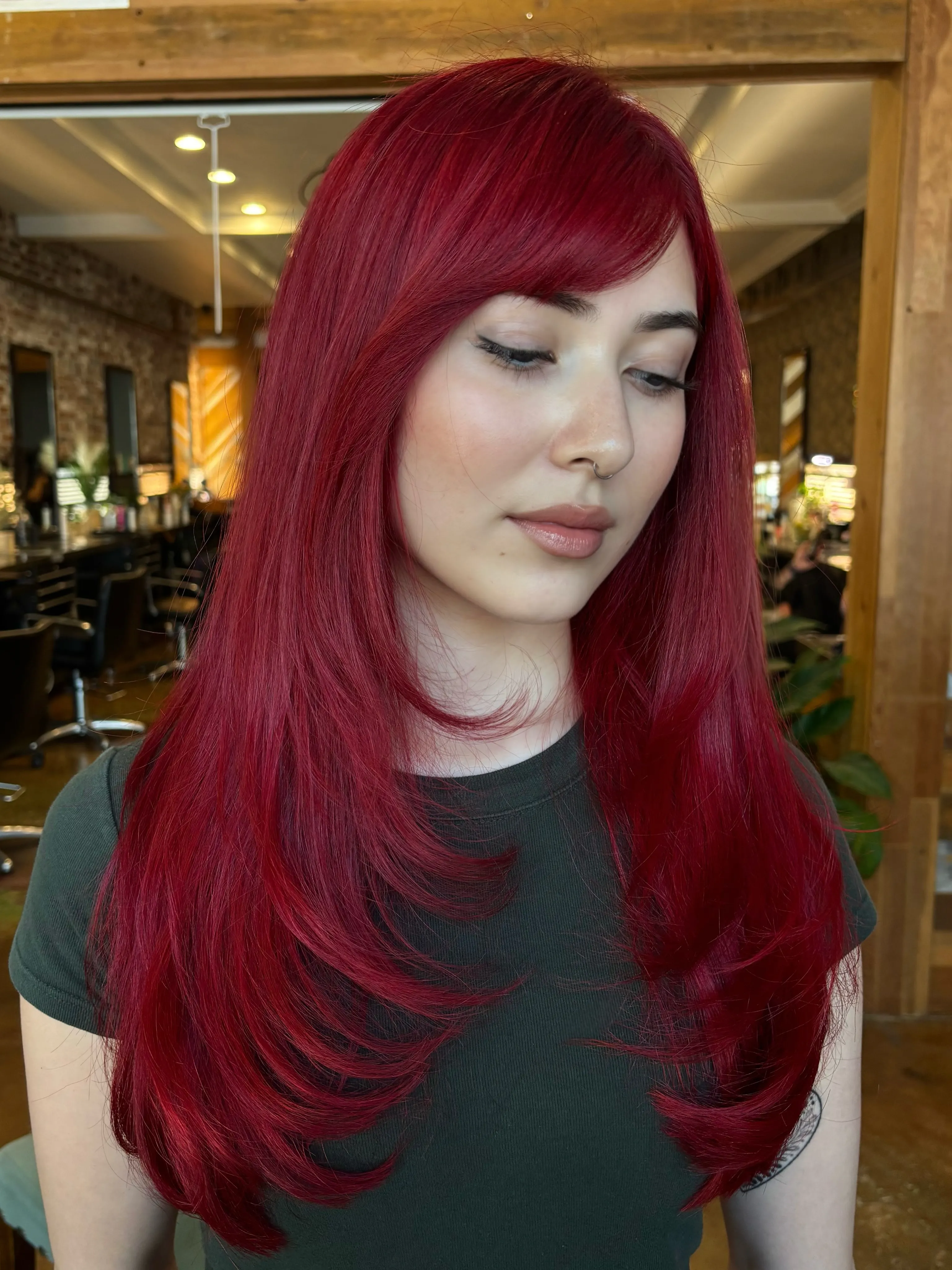 Long ruby-red layered hair with a side-swept fringe