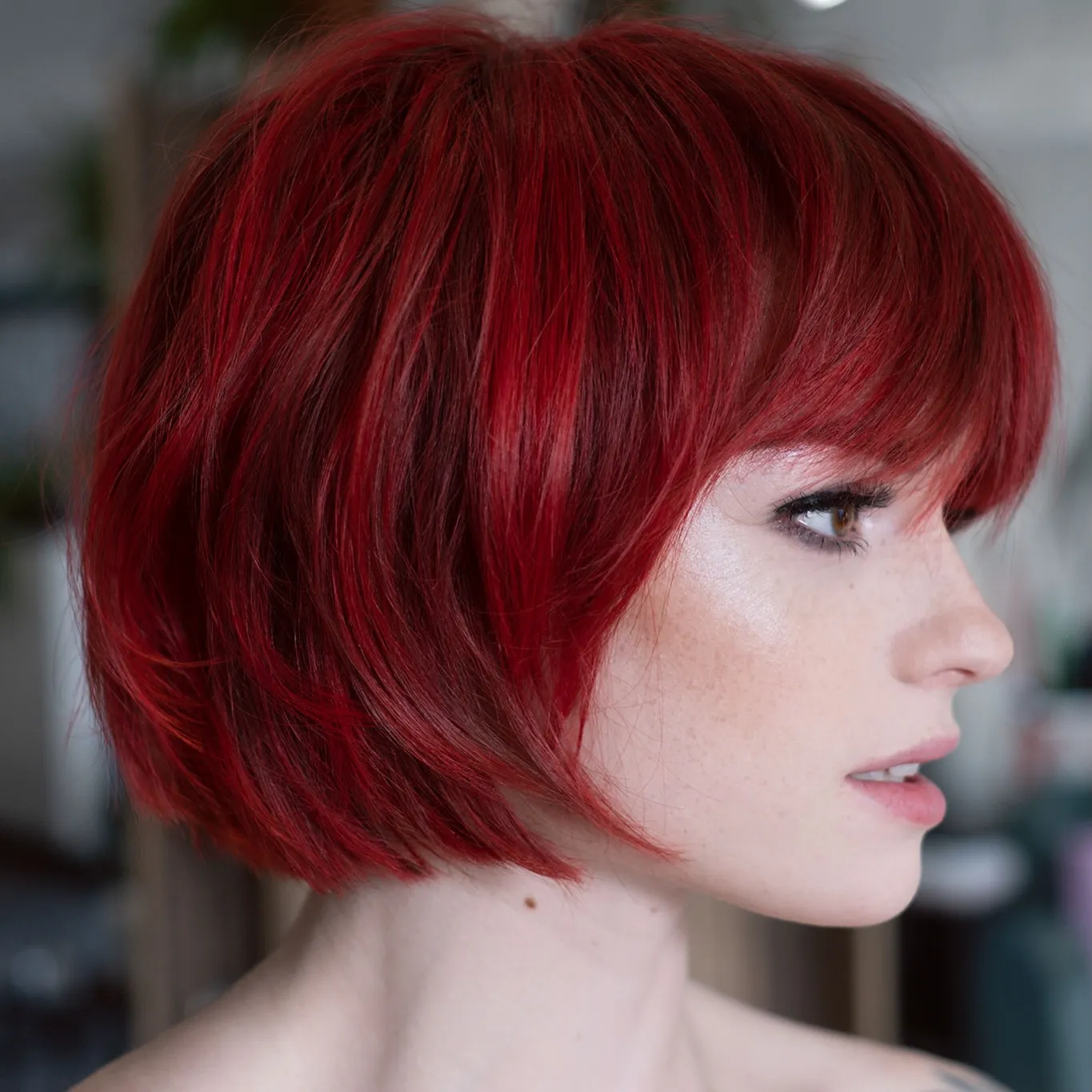 Short crimson-red French bob with a full fringe