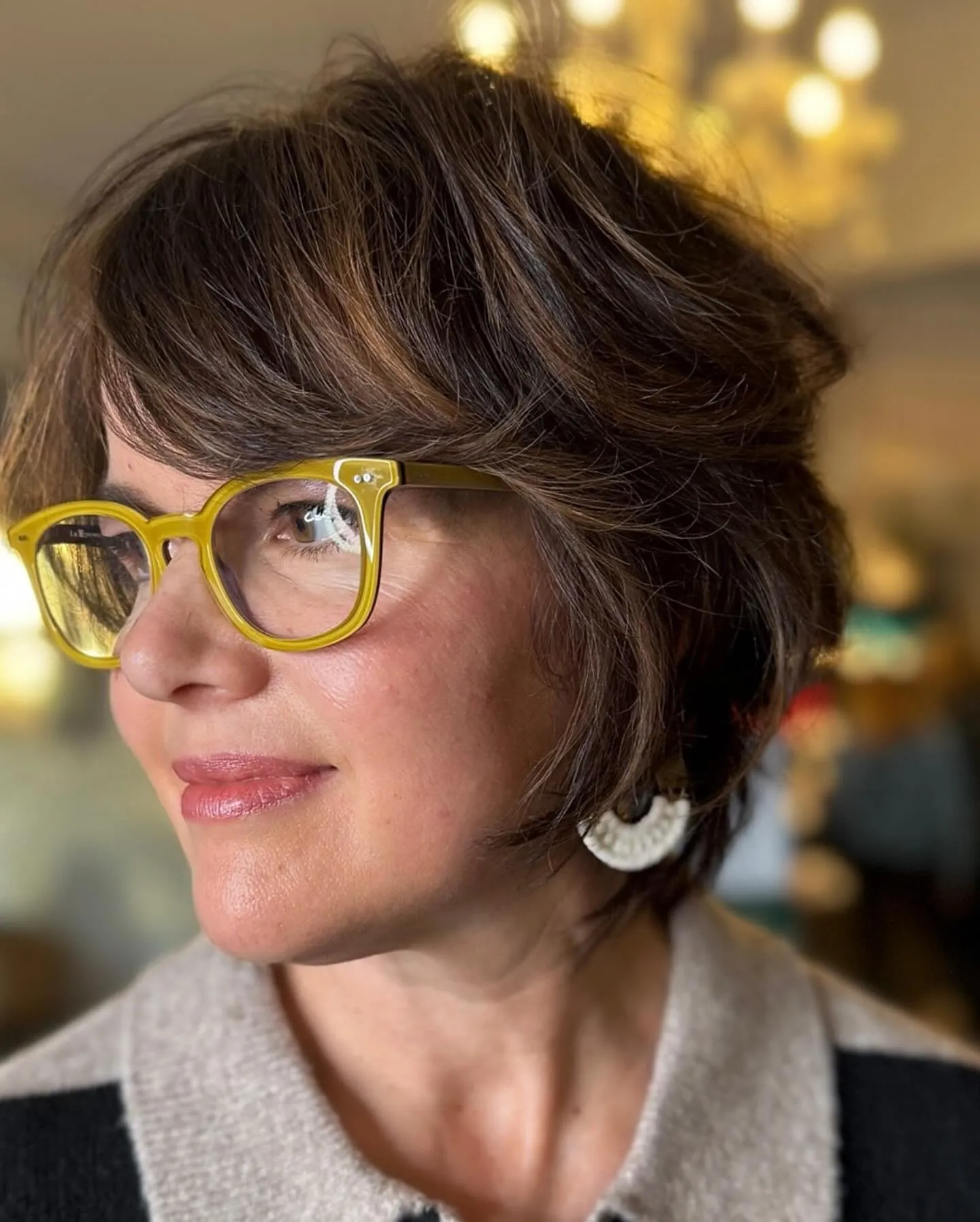 Rounded layered pixie with side fringe and yellow glasses