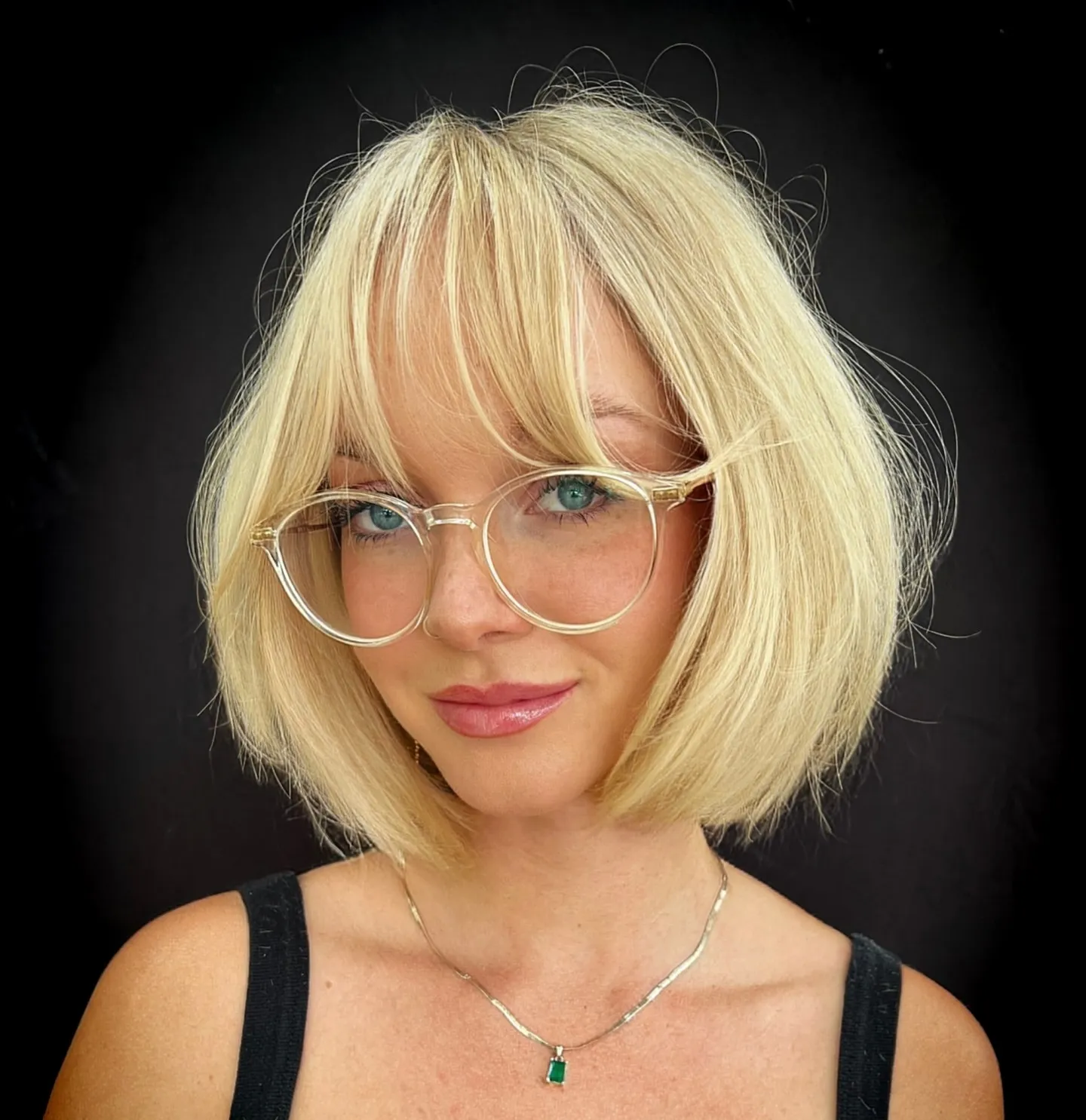 Blonde jaw-length bob with curtain fringe and round clear glasses