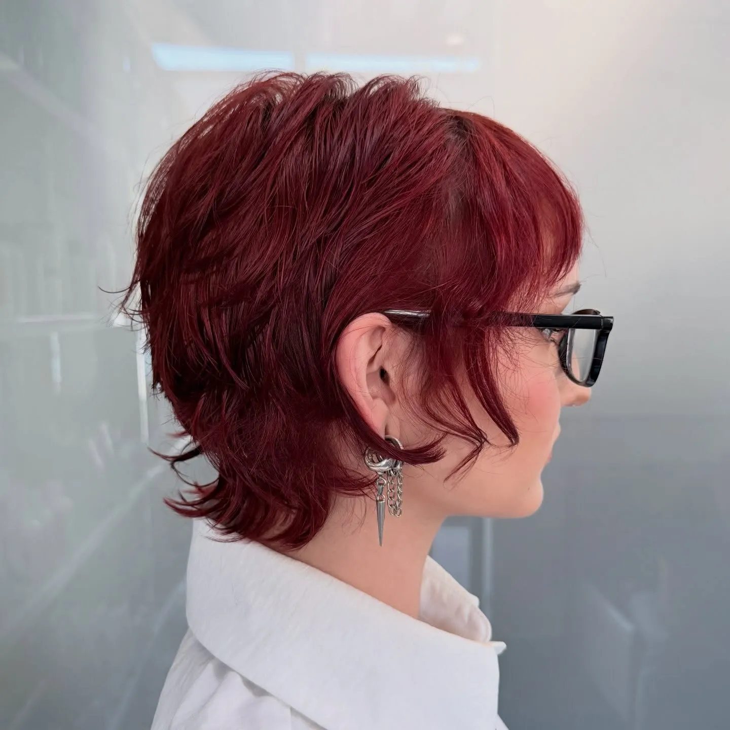 Short red shag mullet with wispy fringe and black glasses