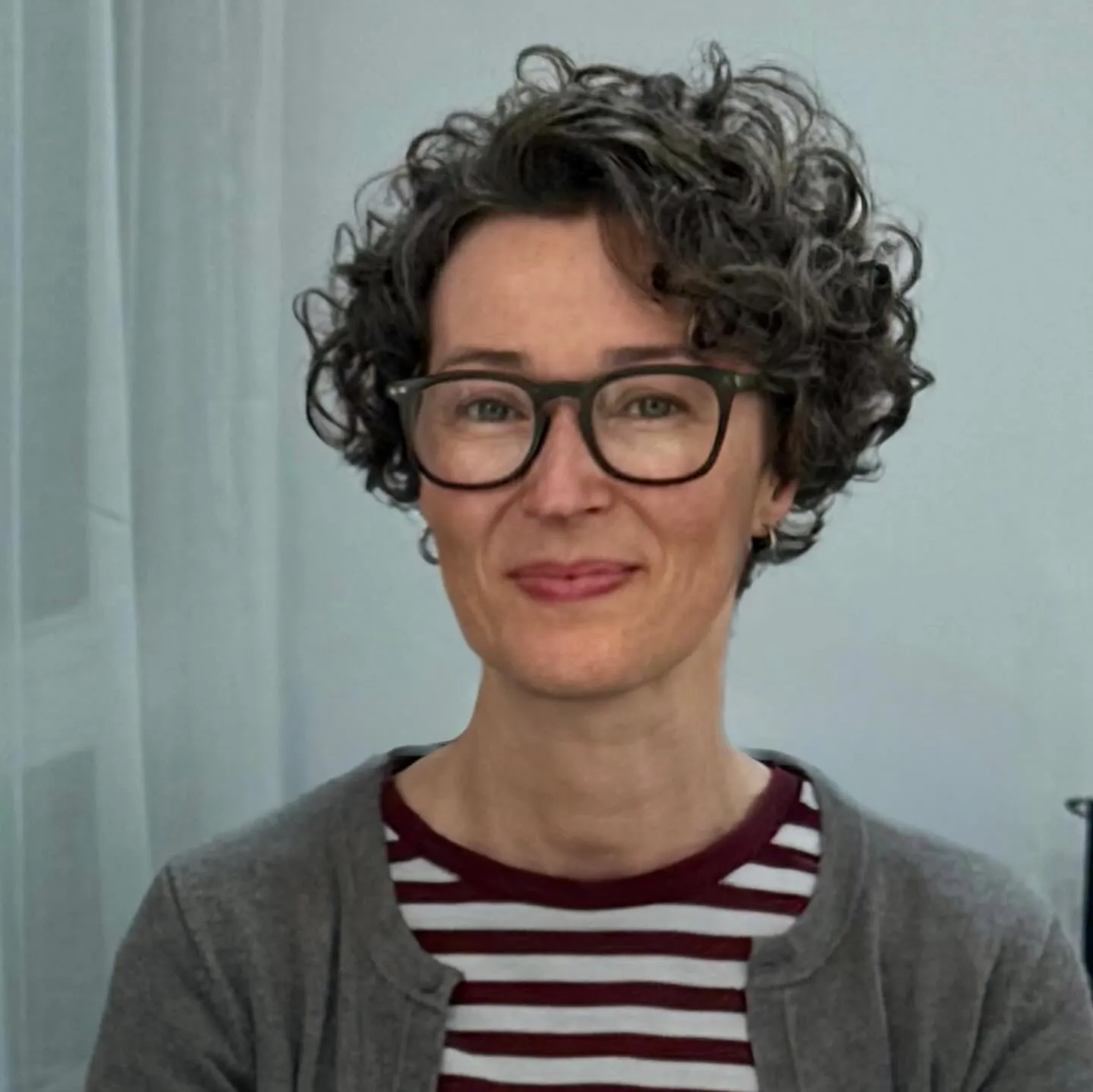 Short curly pixie cut with dark rectangular glasses