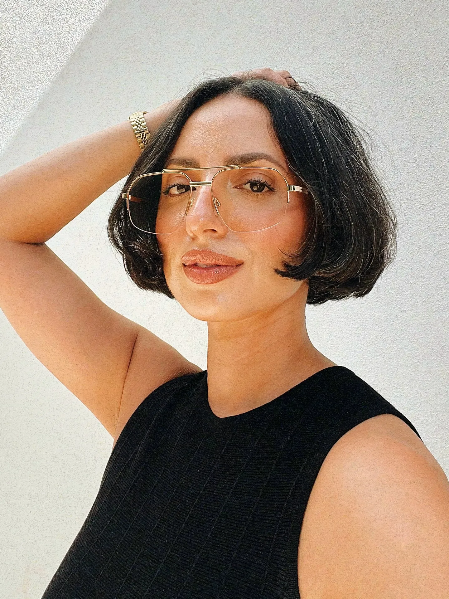Sculpted centre-parted black bob with gold wire glasses