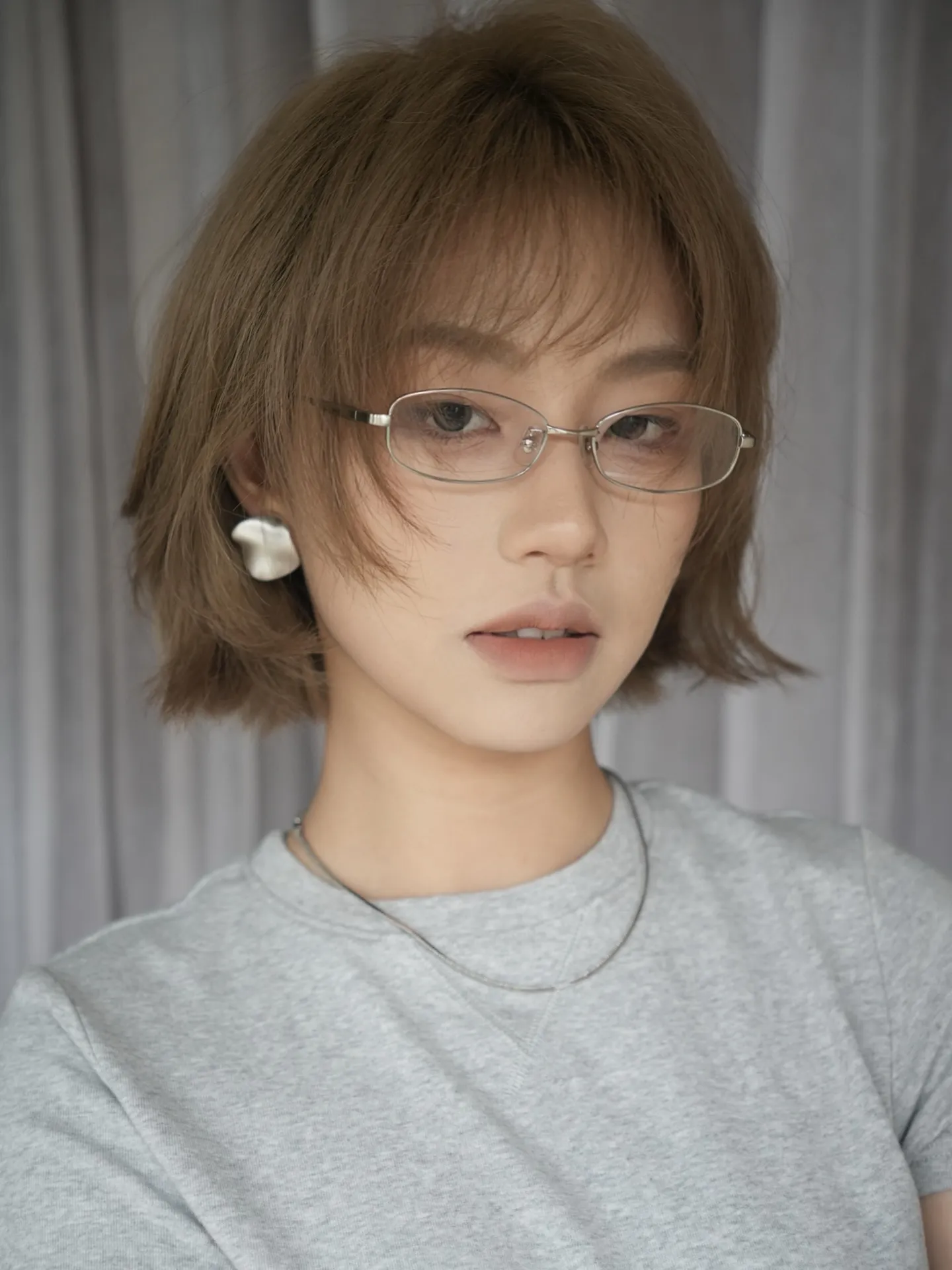 Soft wispy brown bob with airy fringe and narrow metal glasses