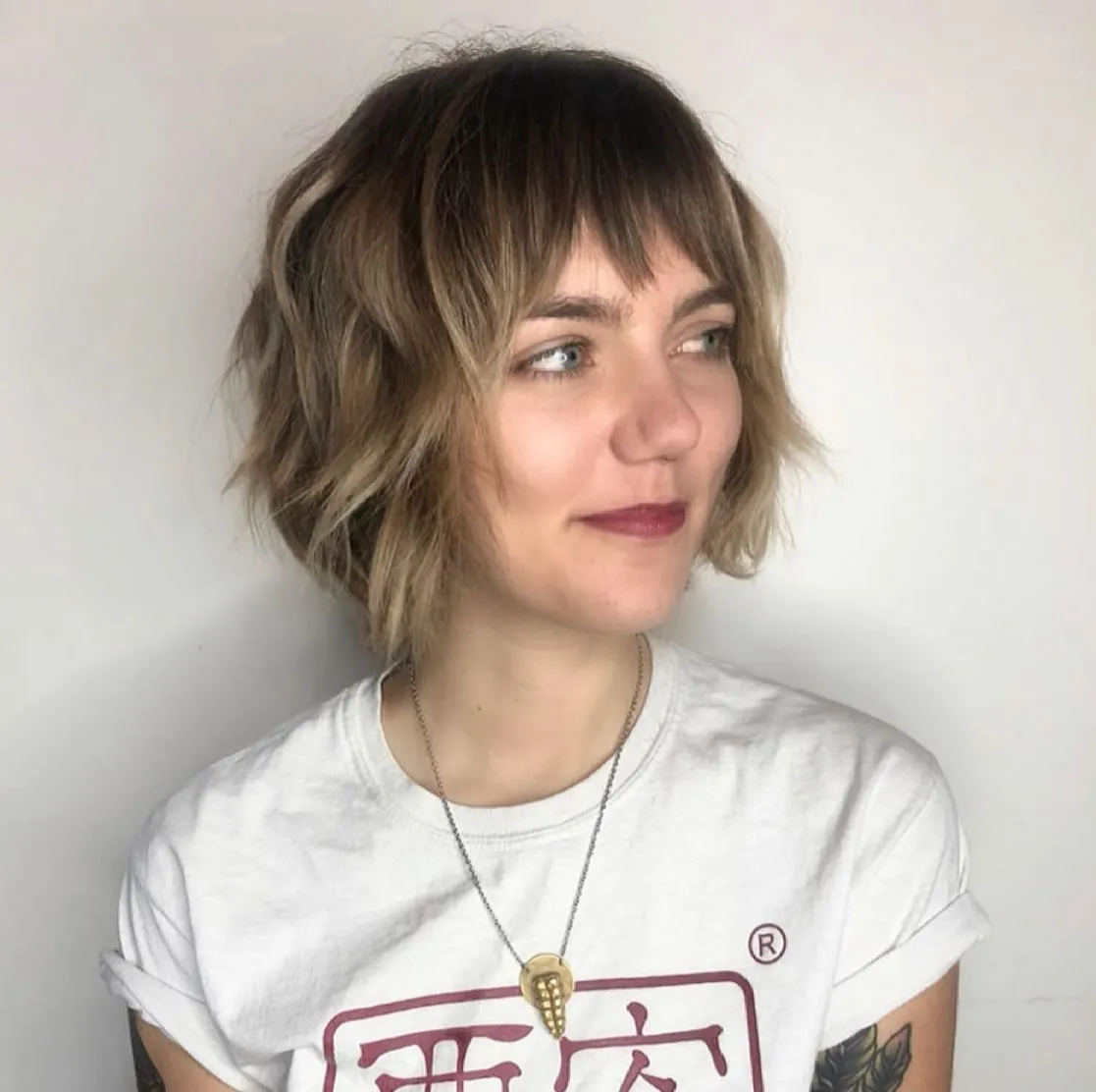 Wavy shaggy bob with feathered full fringe and highlighted jaw-length layers