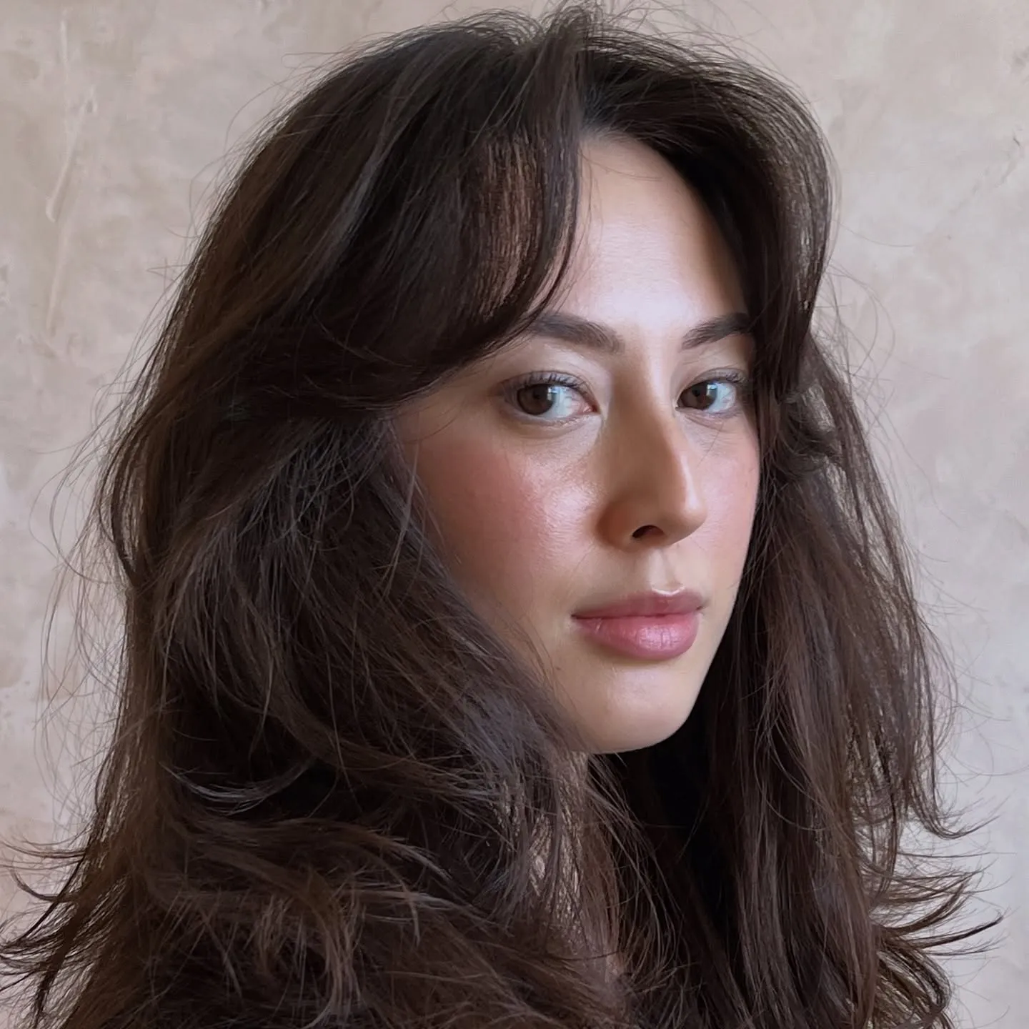 Voluminous shoulder-length layered haircut with curtain fringe and feathered movement