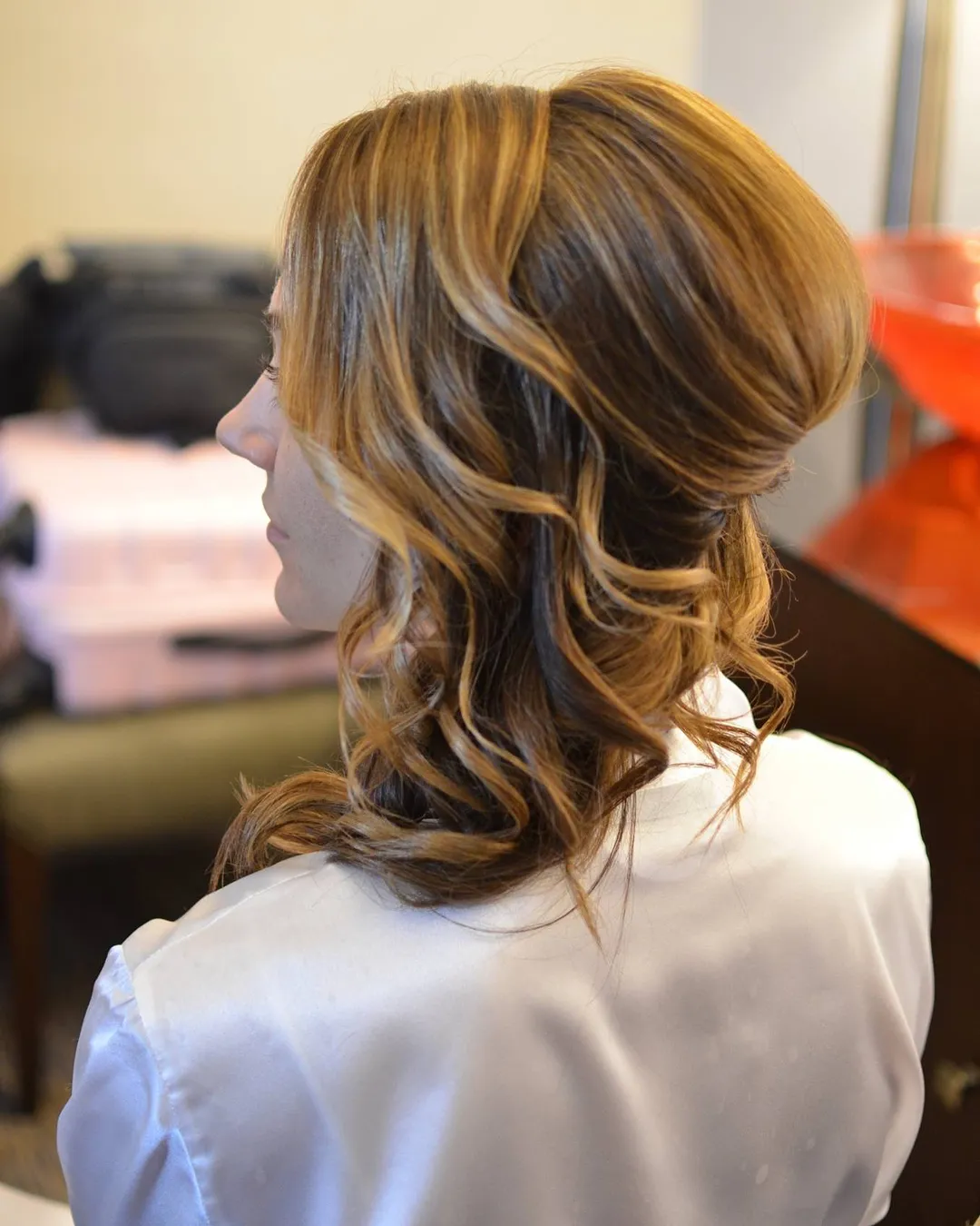 Layered highlighted curls styled into a soft side sweep