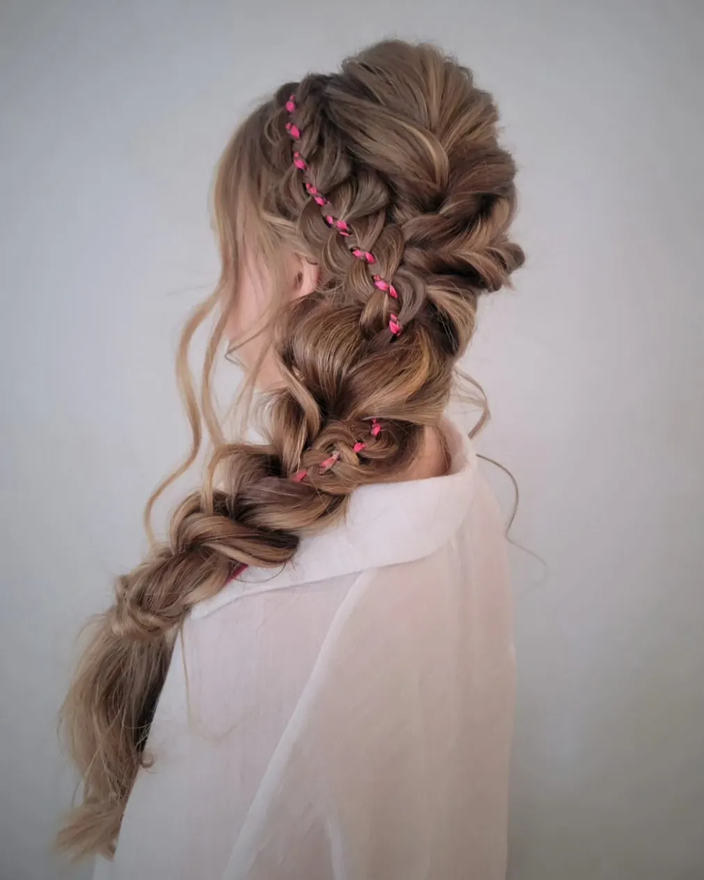 Voluminous side braid with woven pink ribbon accents
