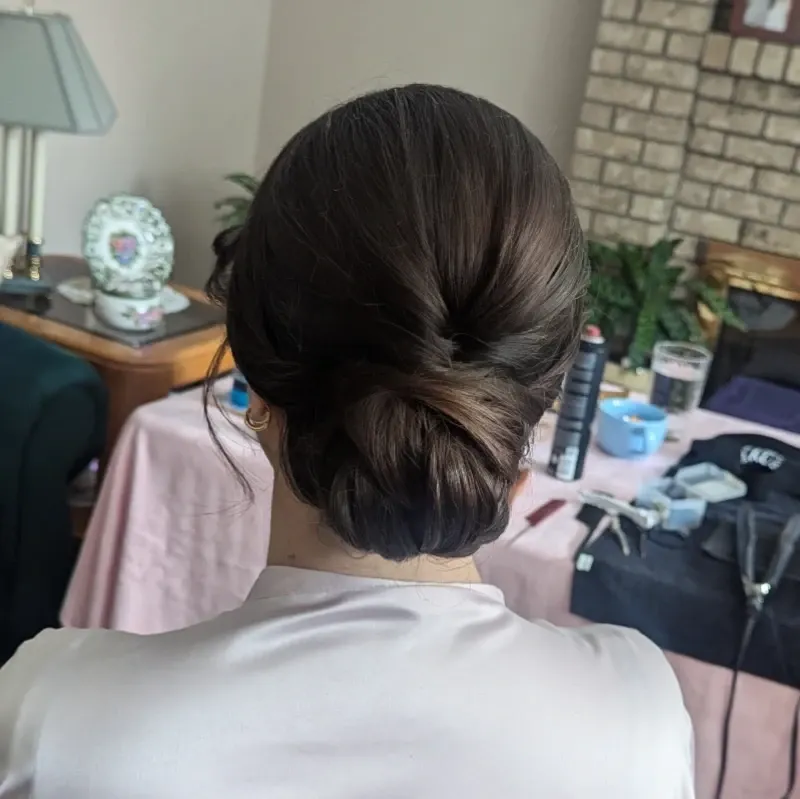 Dark brunette bridal chignon with a smooth crown and soft twisted bun