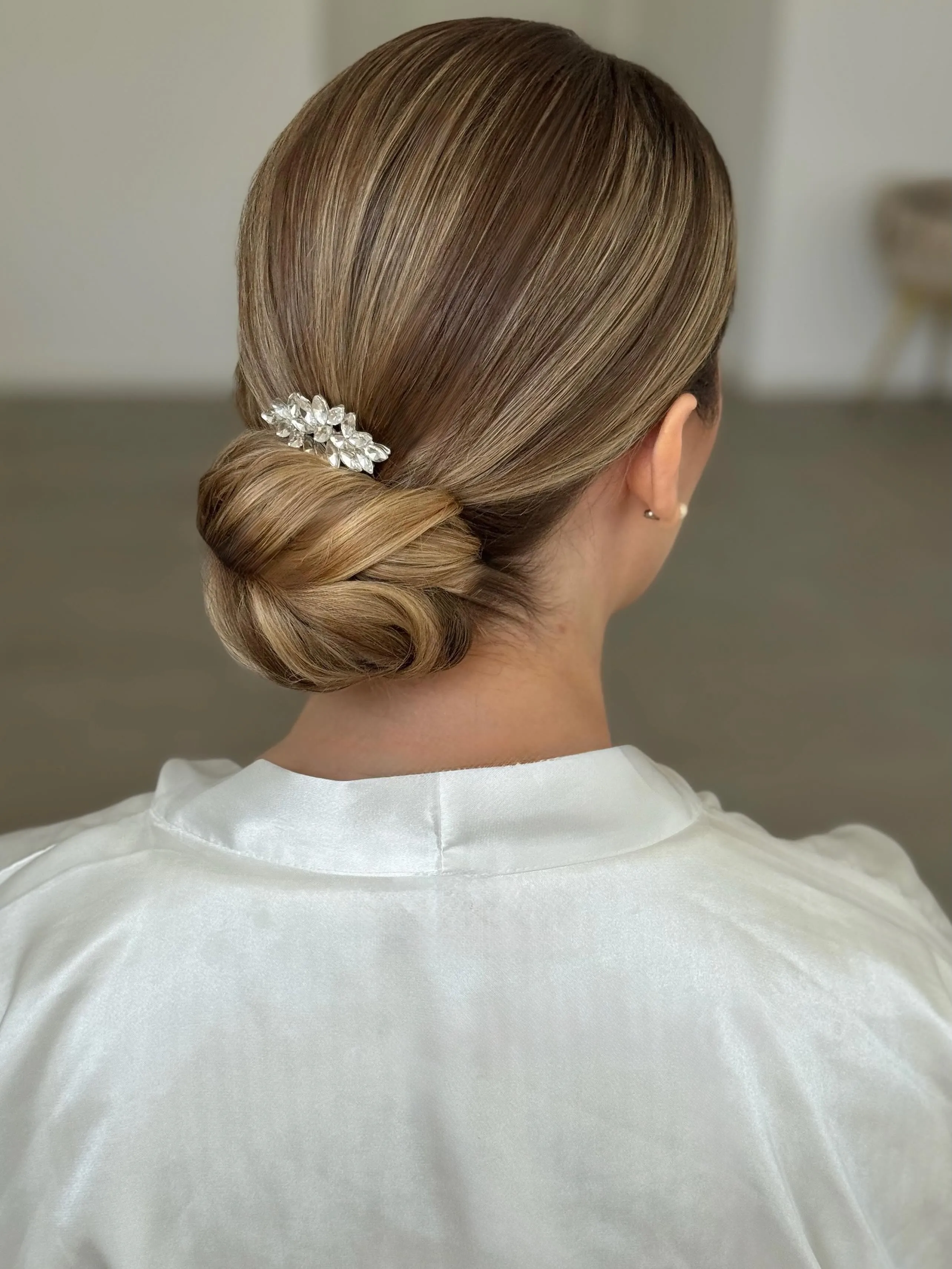 Brunette low bridal bun with a small pearl and crystal comb