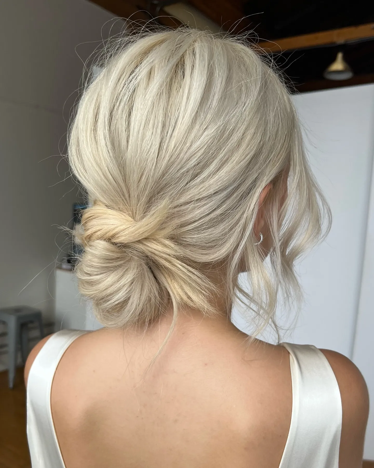 Loose blonde bridal chignon with soft layers and face-framing tendrils