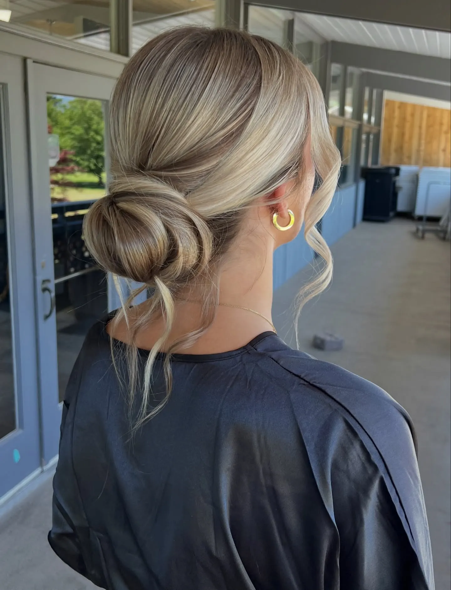 Blonde side-swept bridal bun with loose curled face-framing pieces