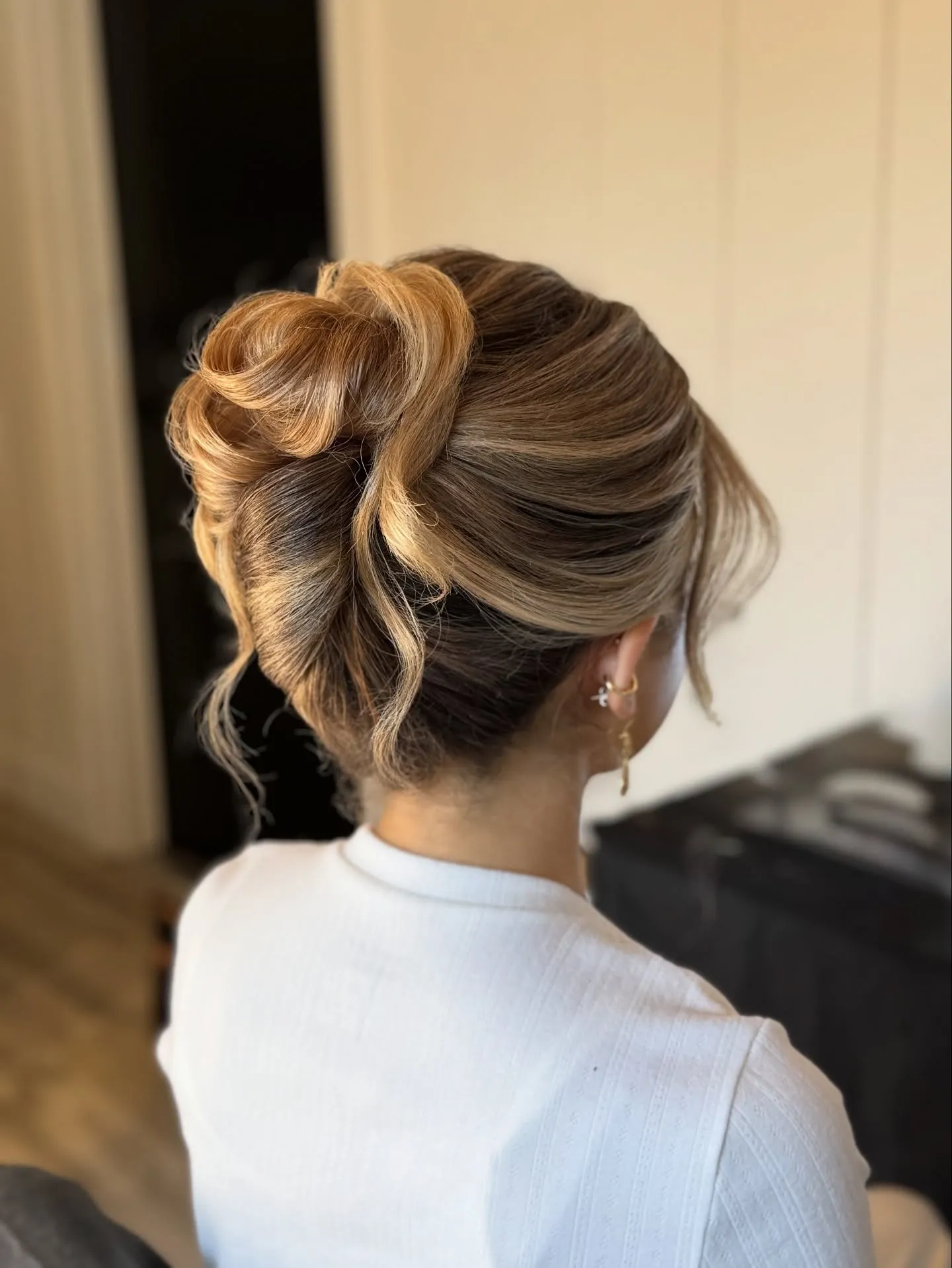Blonde bridal updo with a high looped bun and soft front pieces
