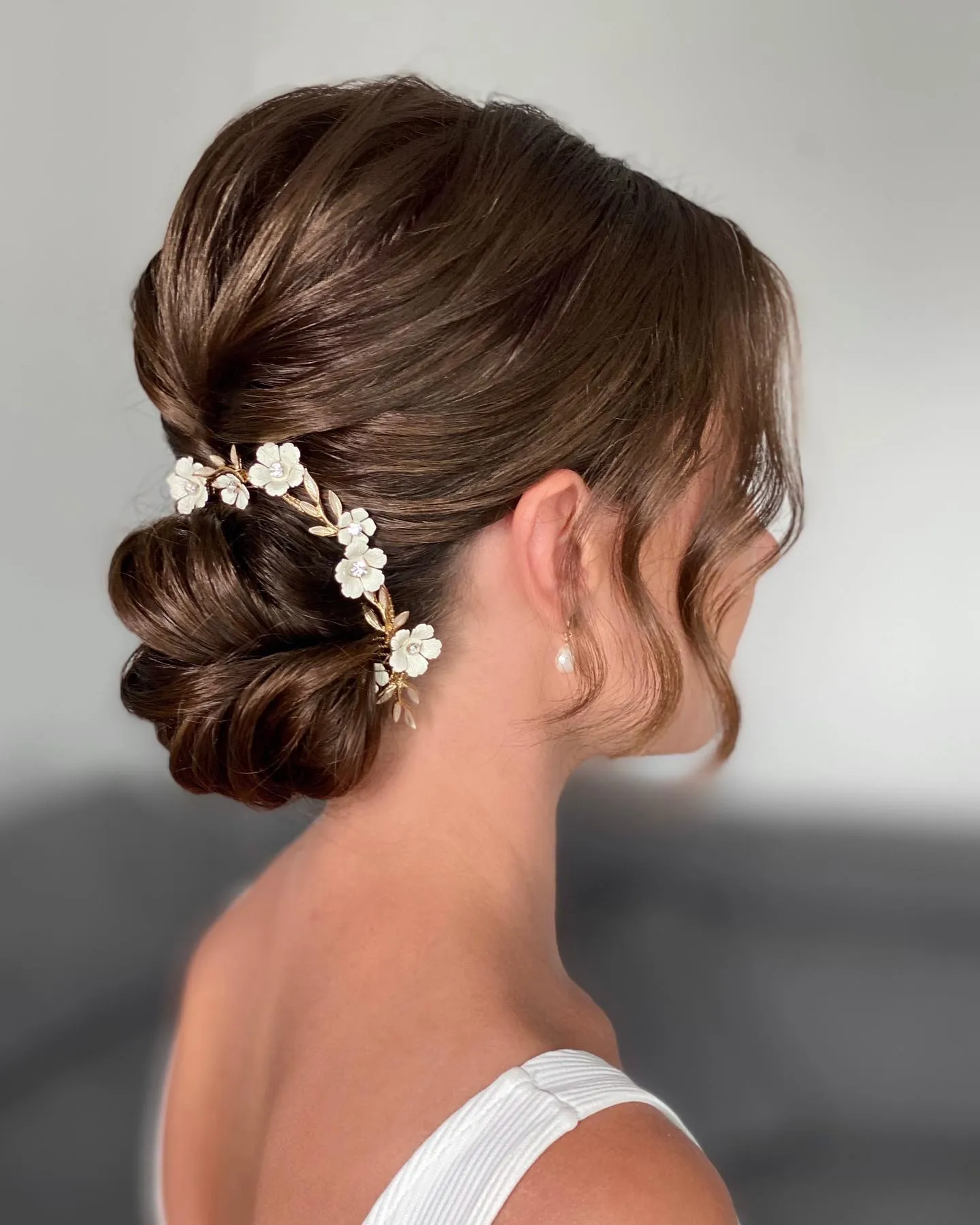 Brunette bridal low bun with delicate white floral hair pins