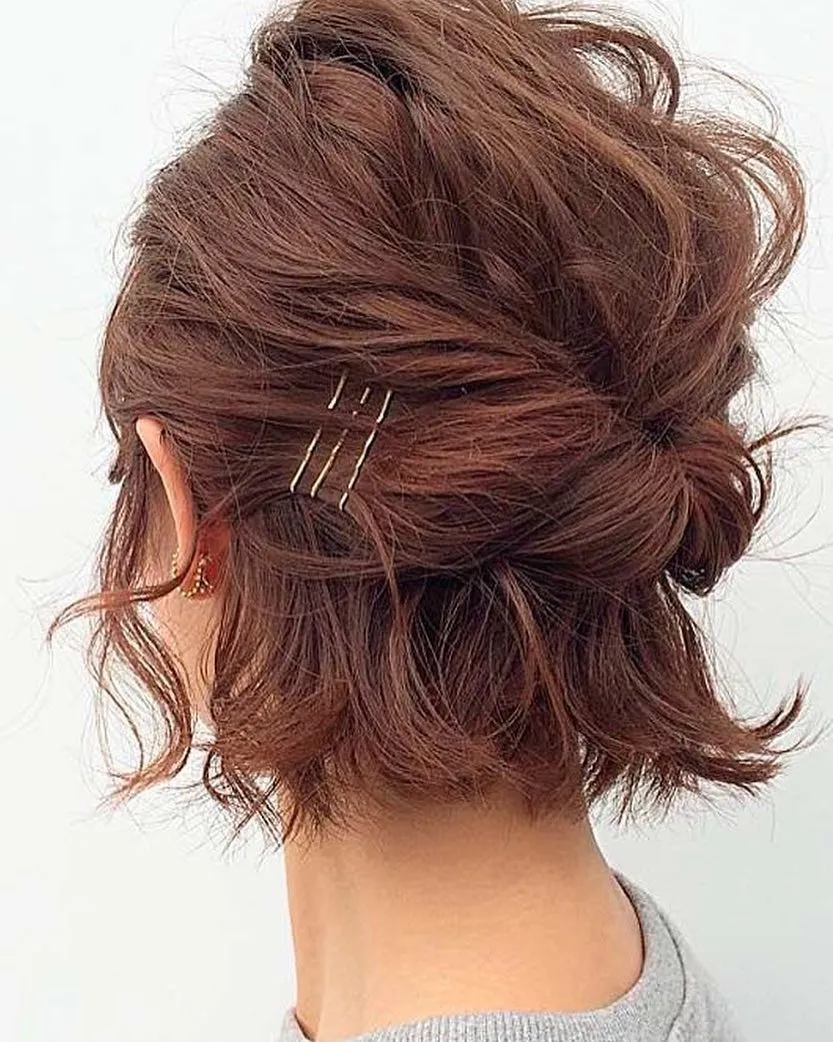 Short auburn bridal updo with pinned texture and loose flipped ends
