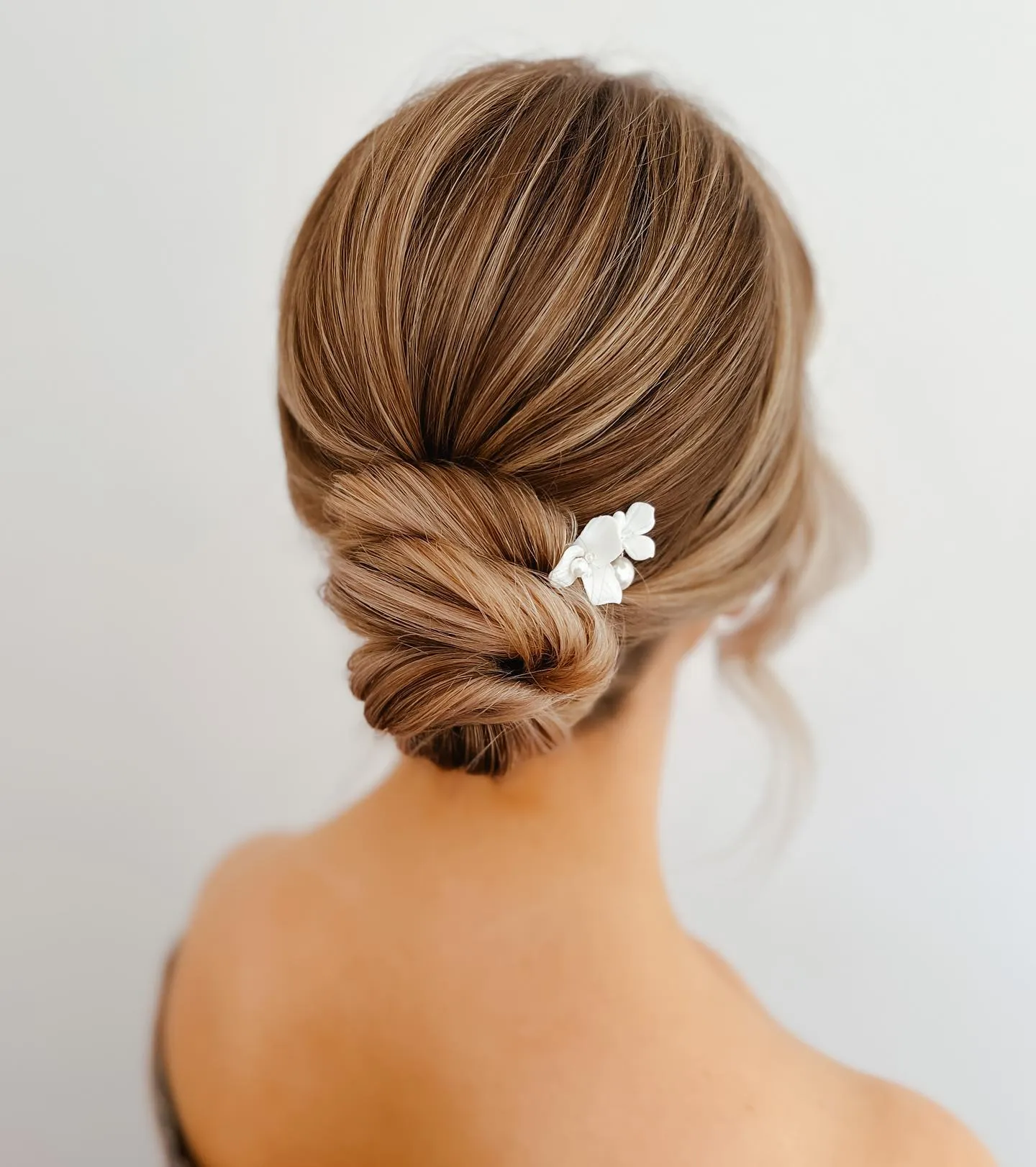 Minimal brunette bridal low knot with a small white floral accent