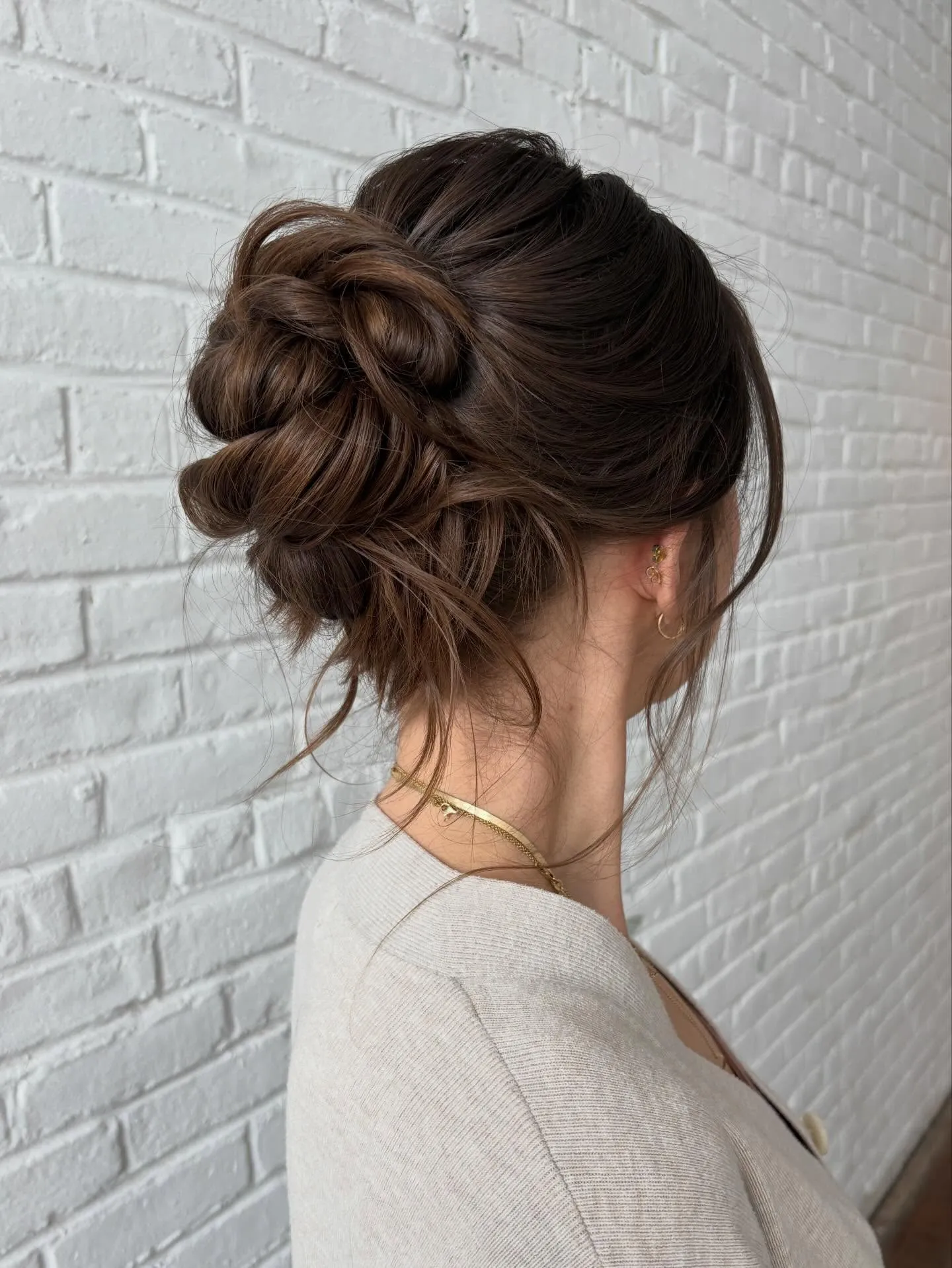 Brunette braided bridal high bun with soft loose tendrils