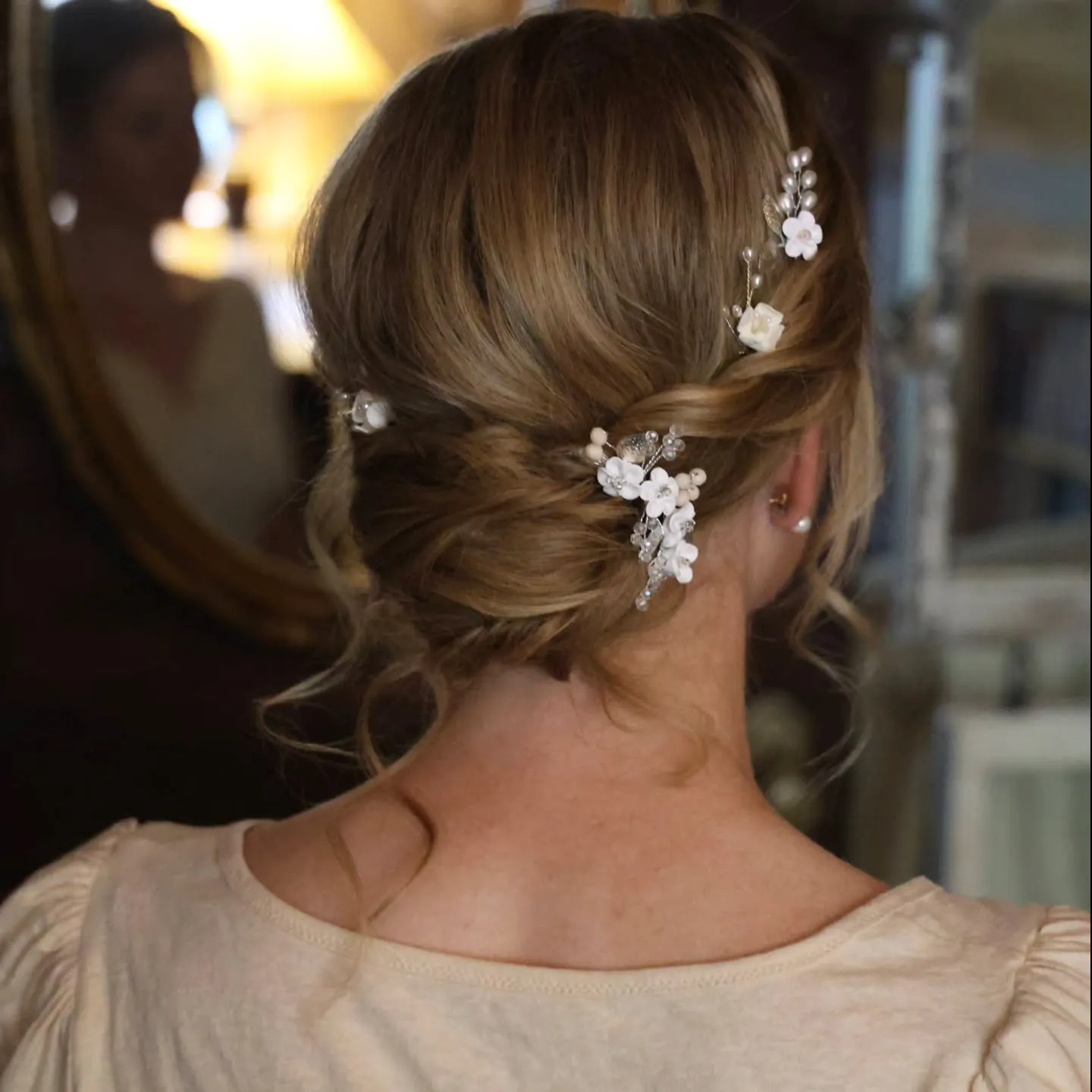 Brunette twisted bridal bun with small white floral hair pins