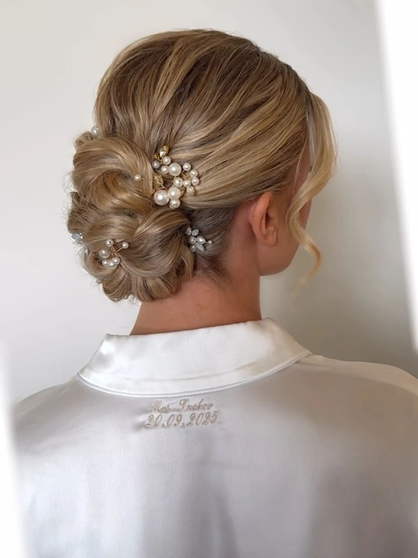 Blonde textured bridal bun with pearl pins and small floral accents