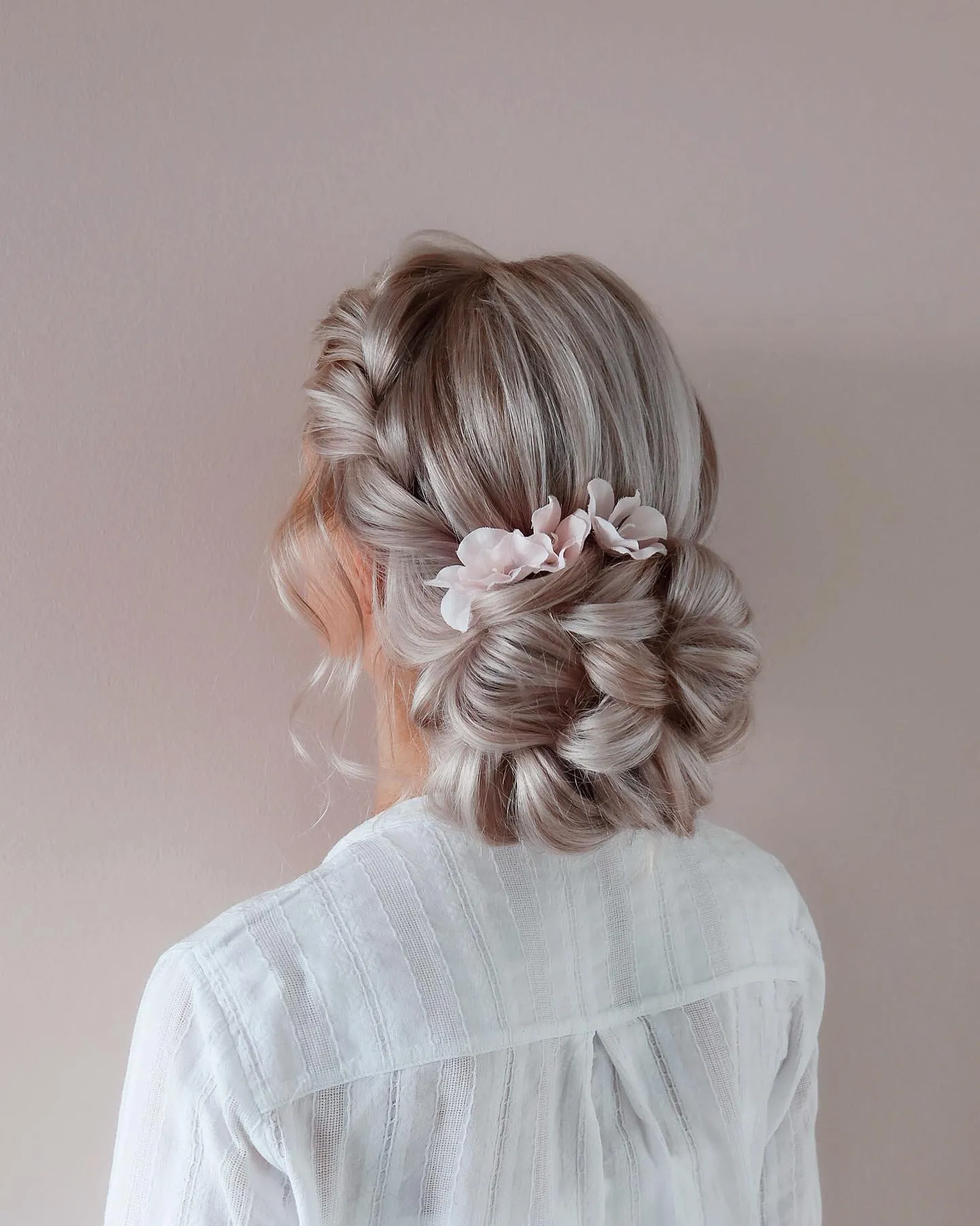 Blonde bridal bun with soft twisted sections and pale floral hair pins