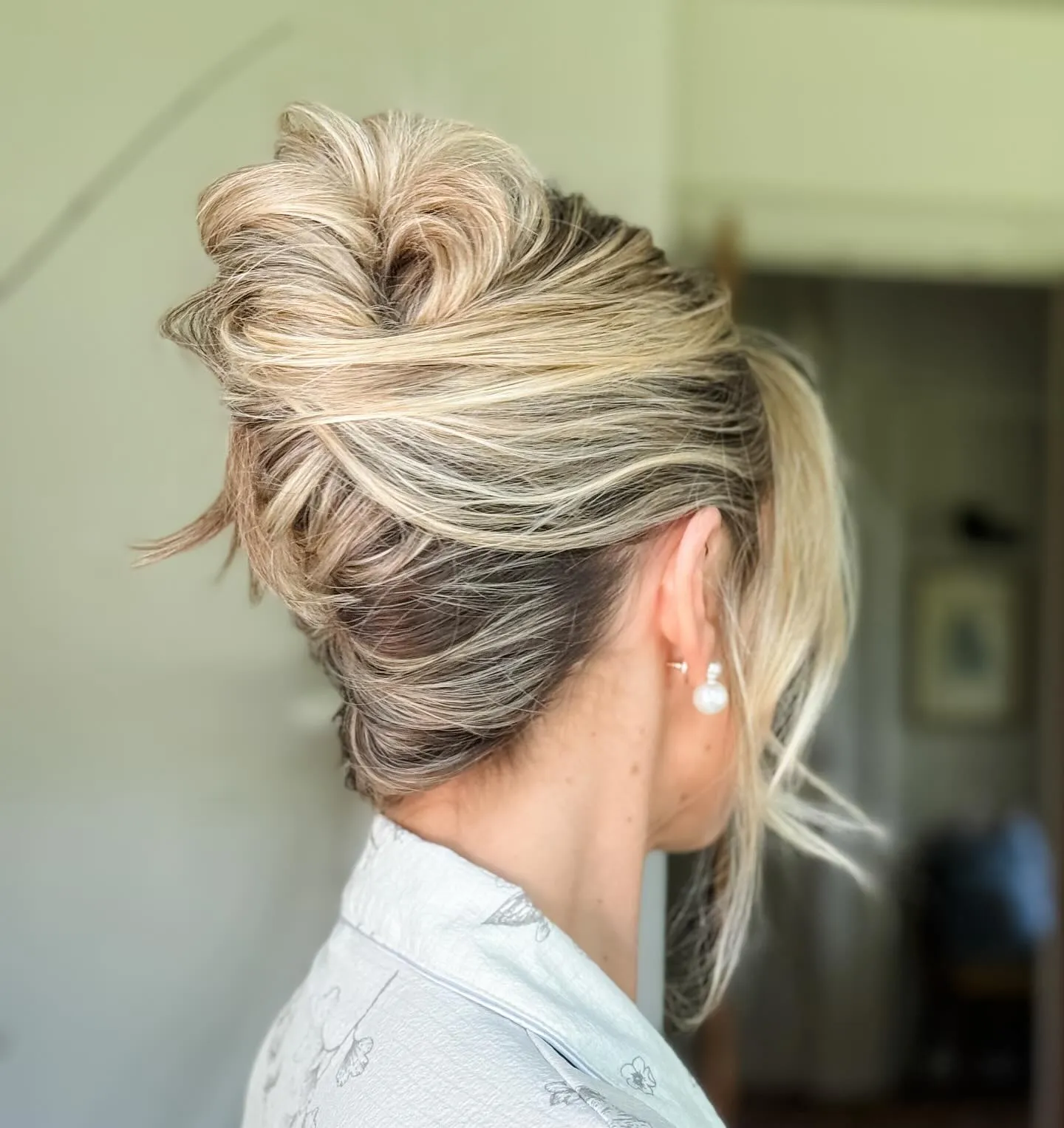 Blonde bridal French twist updo with soft height and face-framing pieces