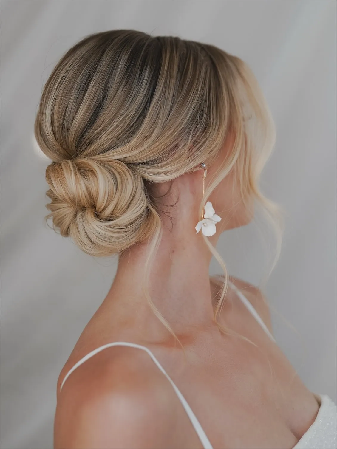 Smooth blonde bridal side bun with a softly curved front section
