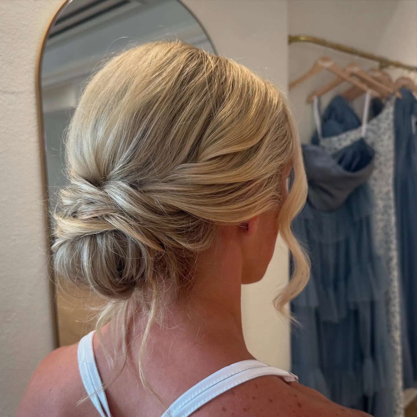 Blonde soft bridal low bun with smooth sides and loose face-framing curl