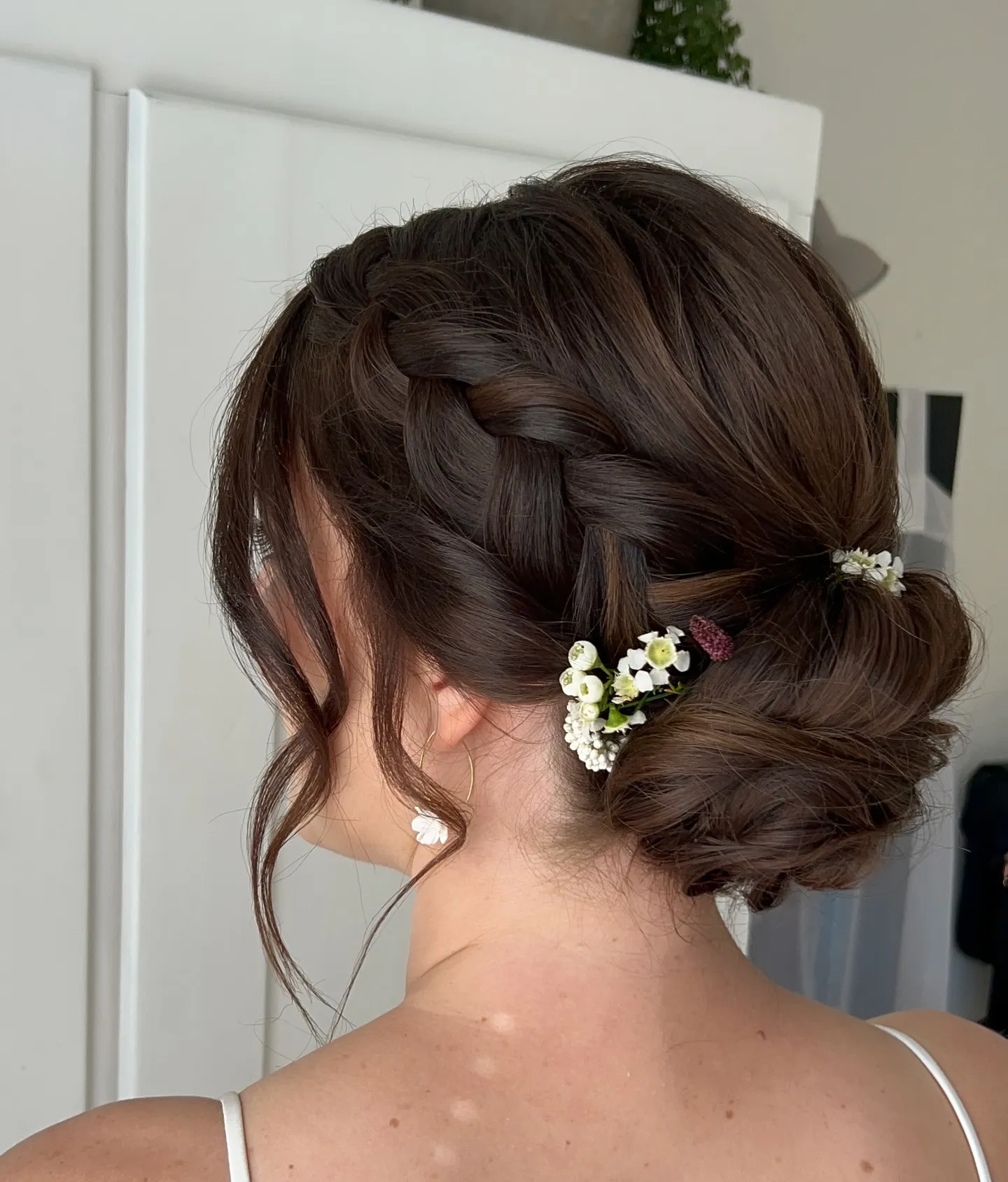 Brunette braided bridal low bun with tiny white floral accents