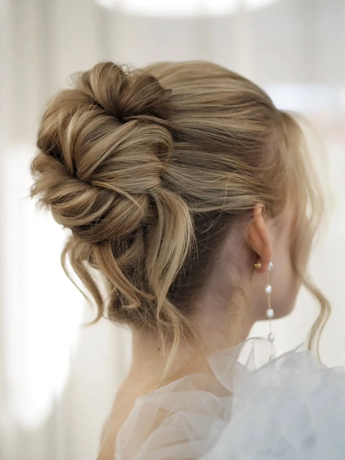 Textured blonde bridal bun with loose face-framing pieces