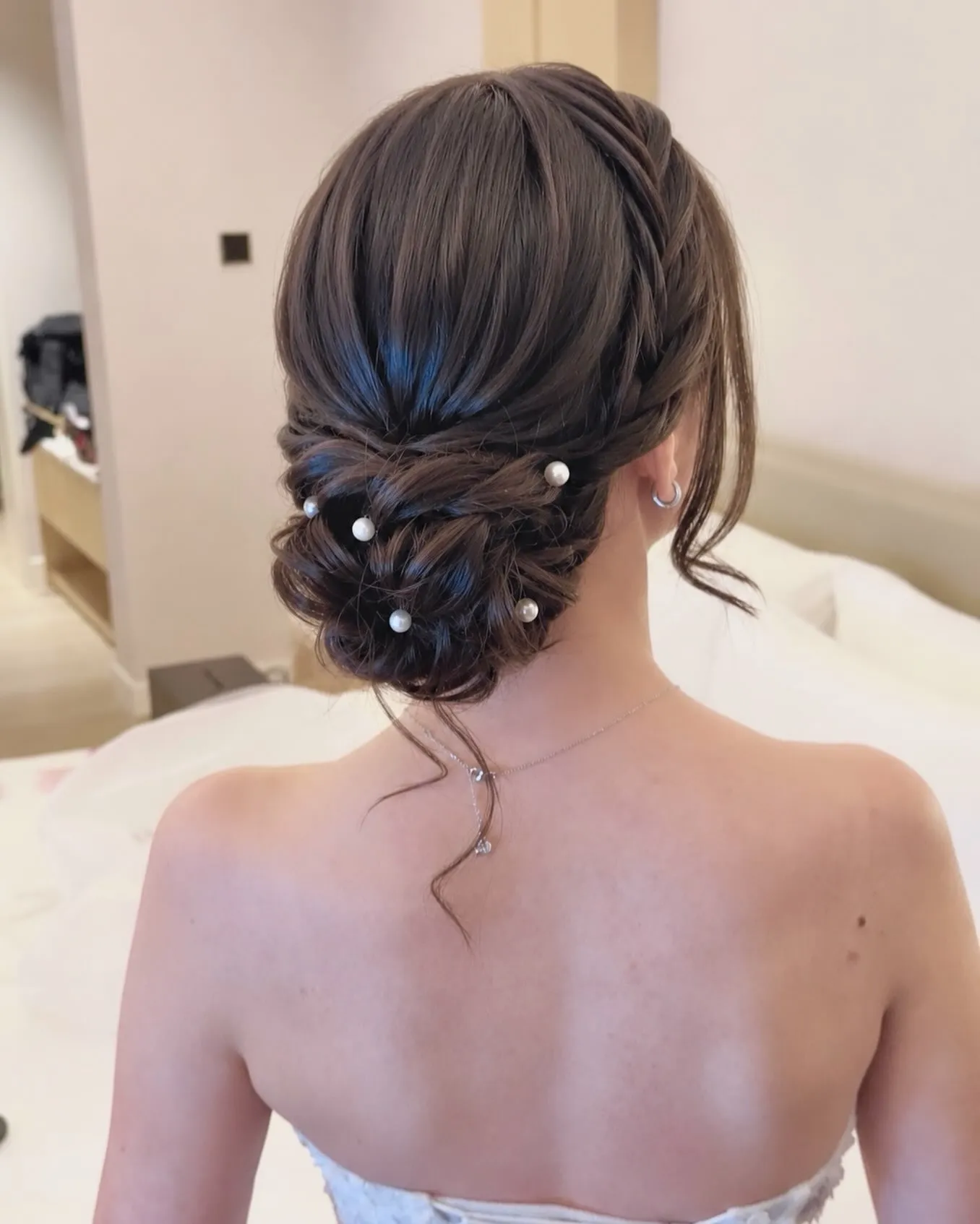 Dark low bridal chignon with scattered pearl hair pins