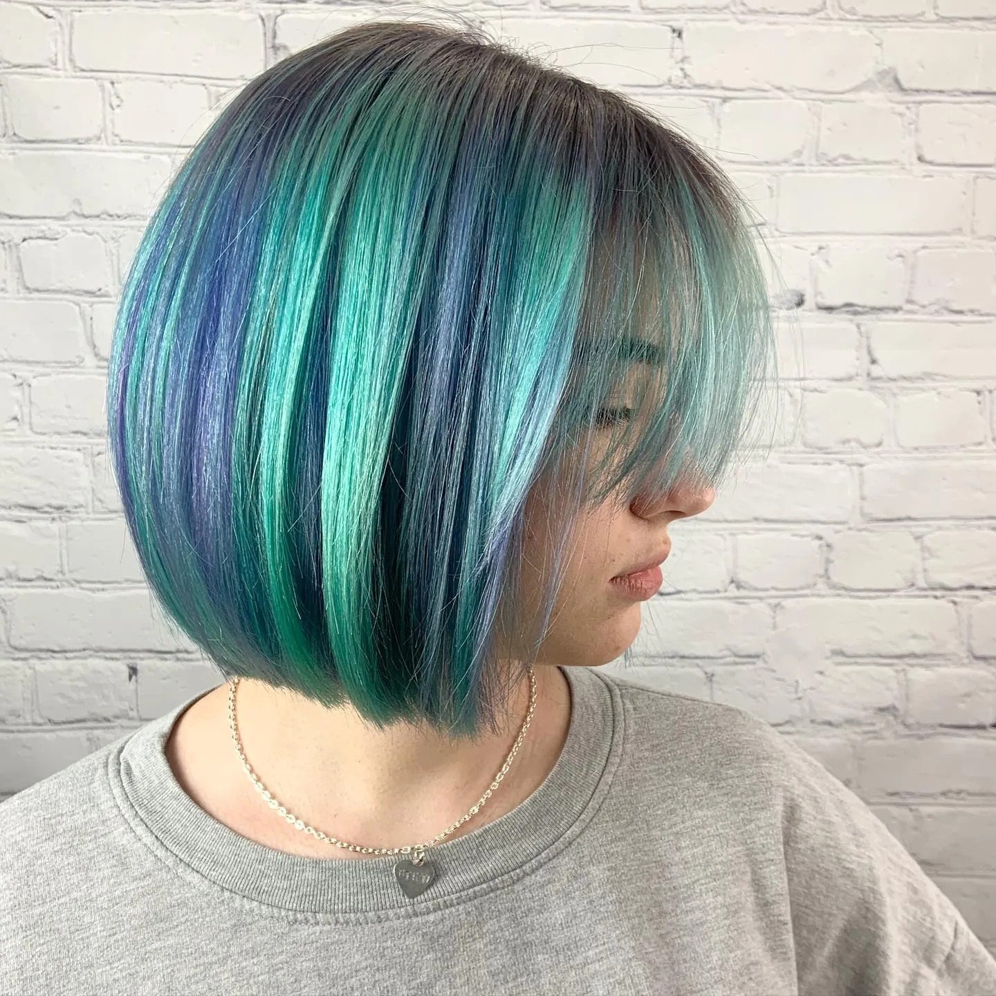 Vivid teal blunt bob with a long sweeping fringe