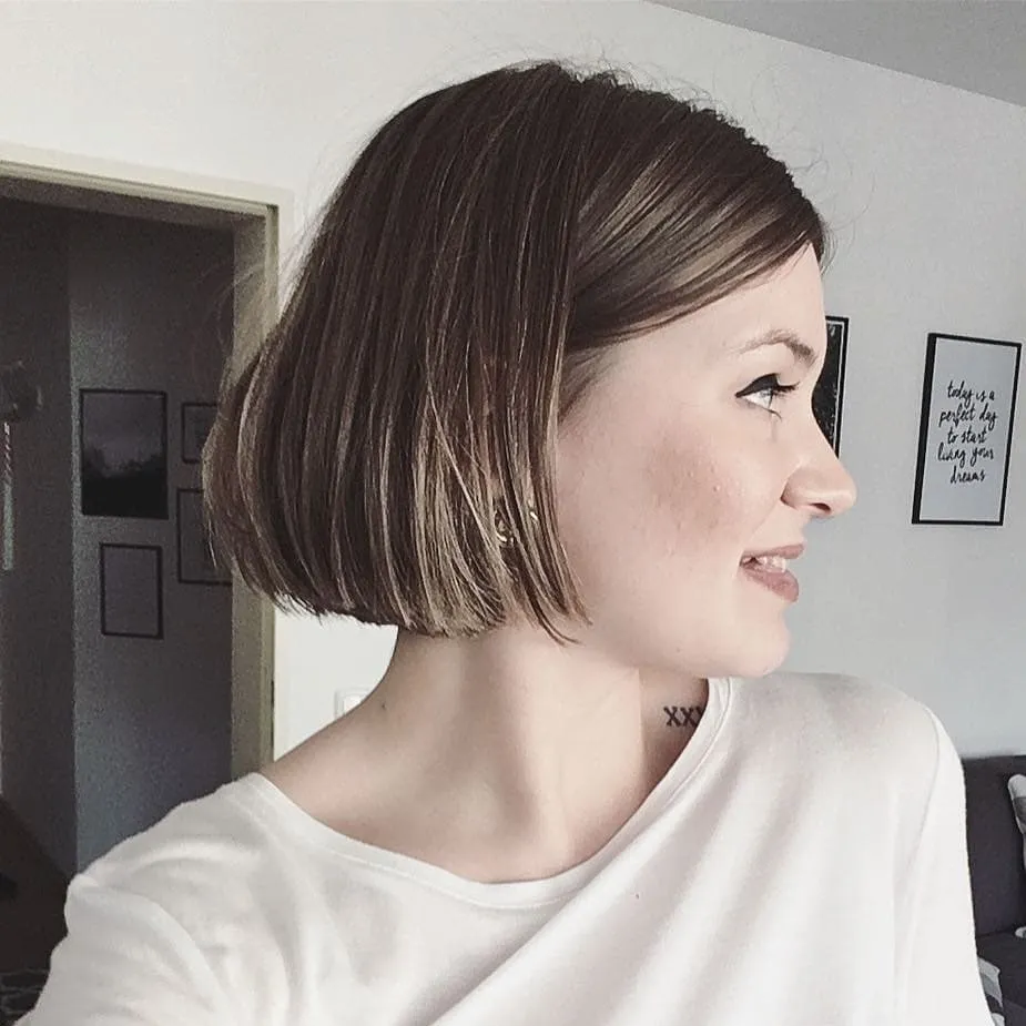 Sleek brunette straight bob with a side part and chin-length blunt ends