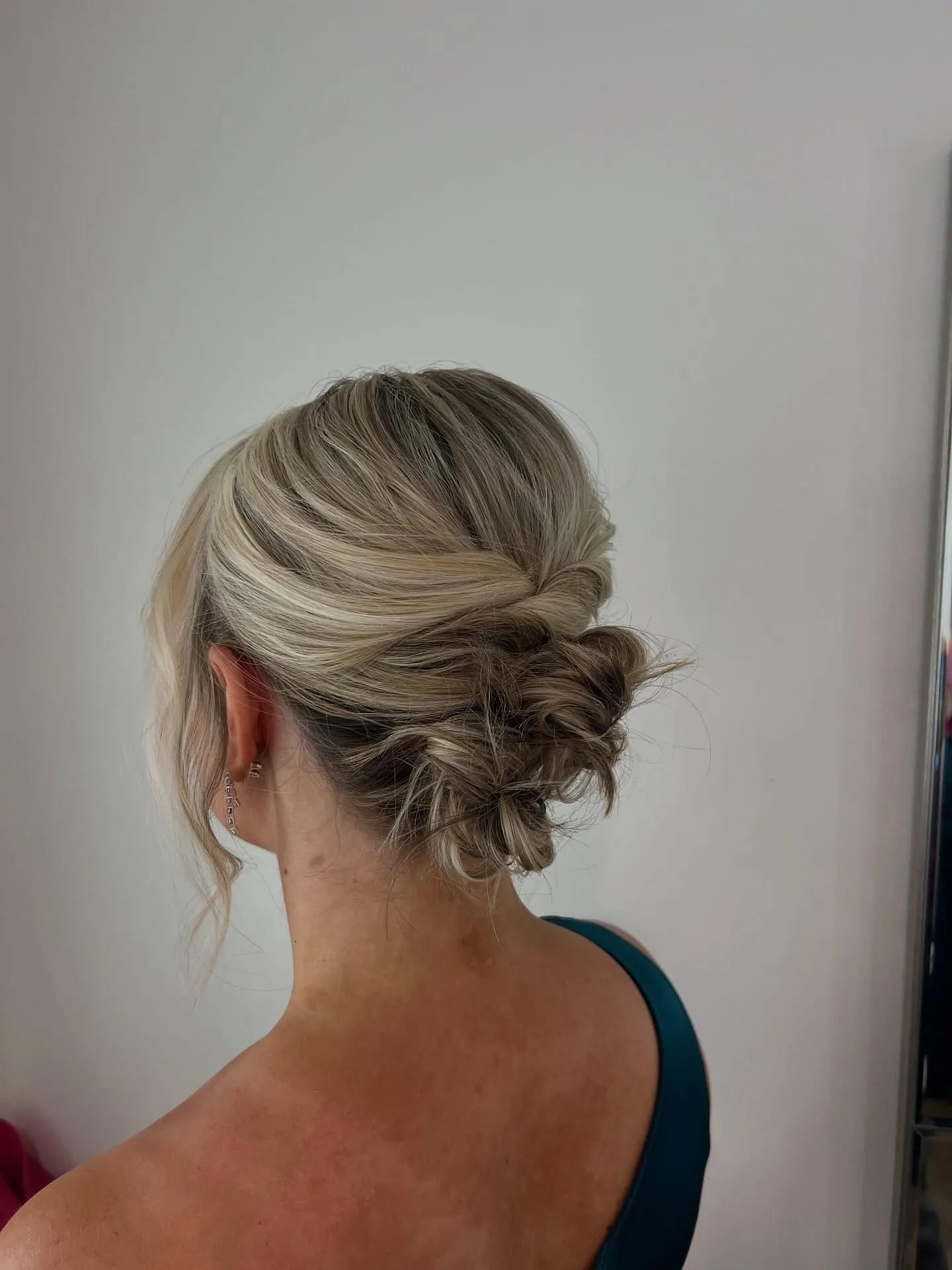 Twisted low bun for short blonde hair with a loose face-framing piece