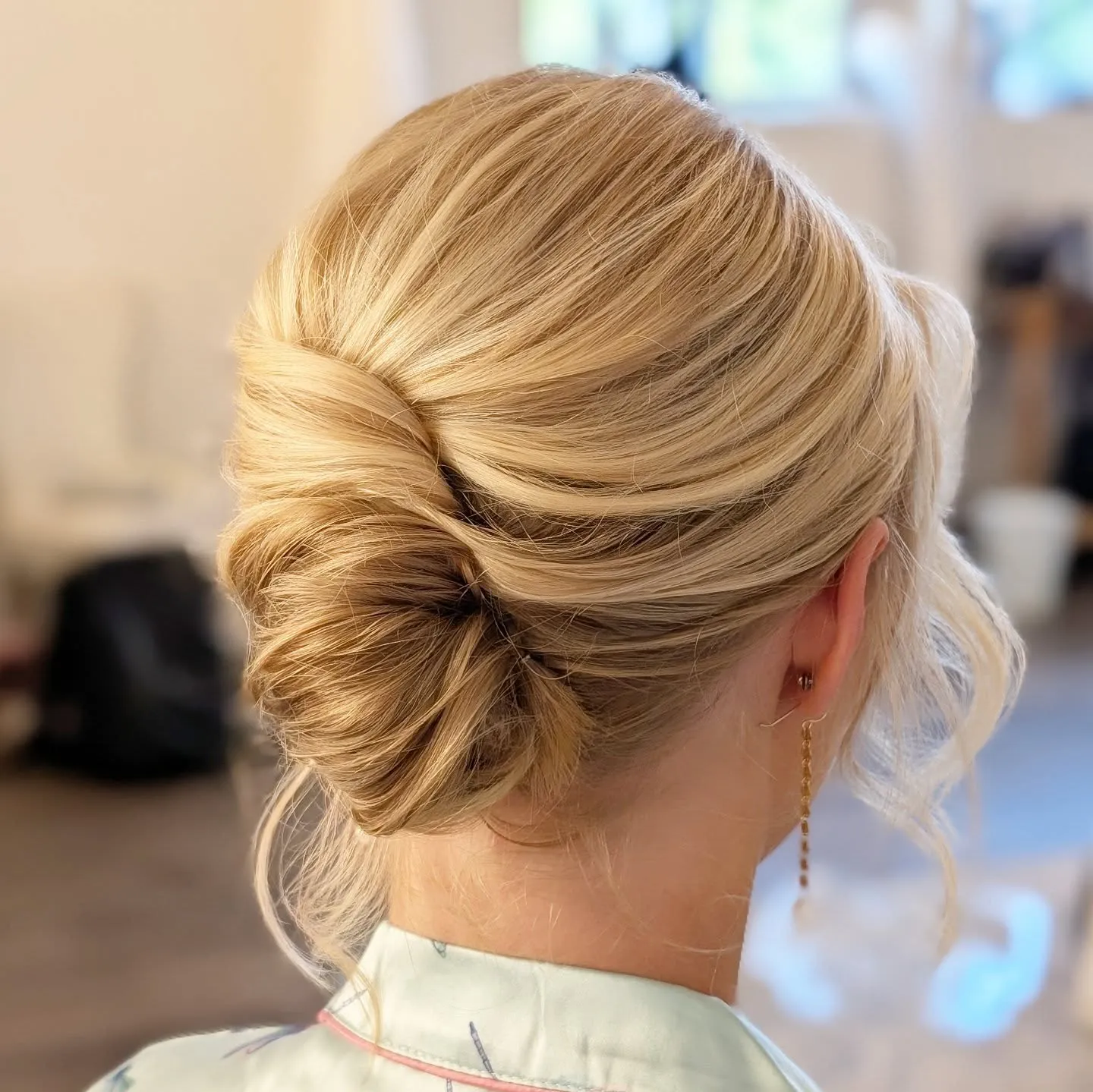 Side-swept low chignon for short blonde hair with a loose curl
