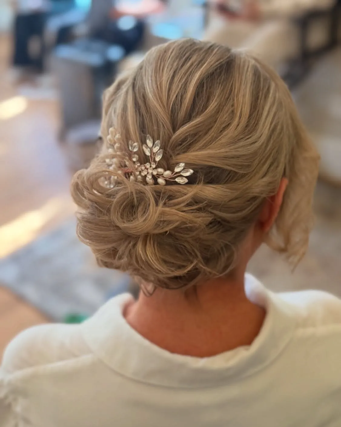 Textured low messy bun for short hair with a jeweled branch