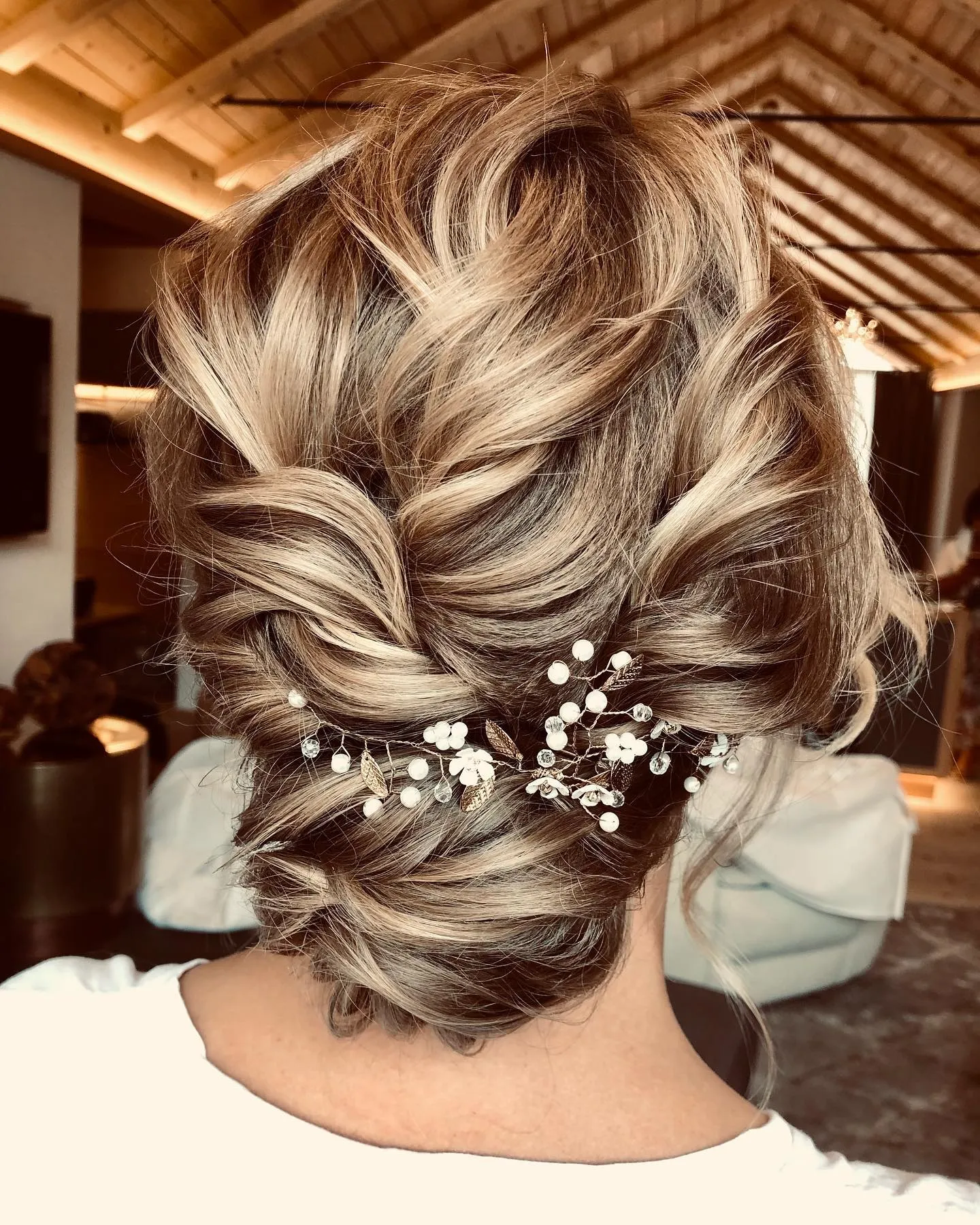 Twisted low chignon for short highlighted hair with a pearl vine