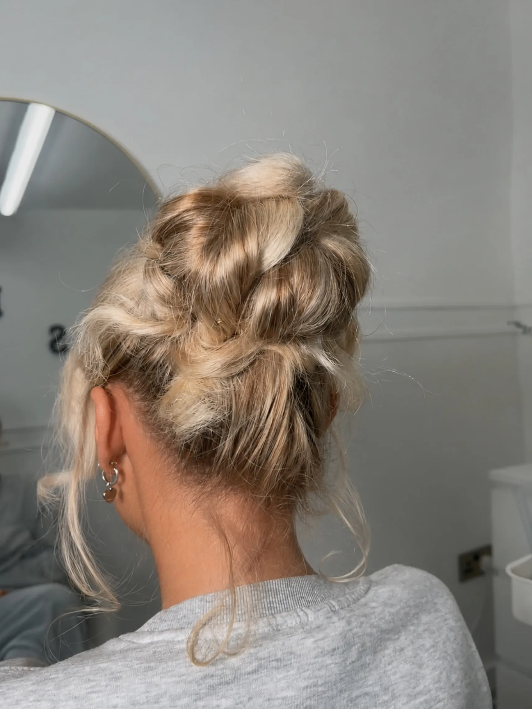 High messy bun for short blonde hair with loose face-framing tendrils