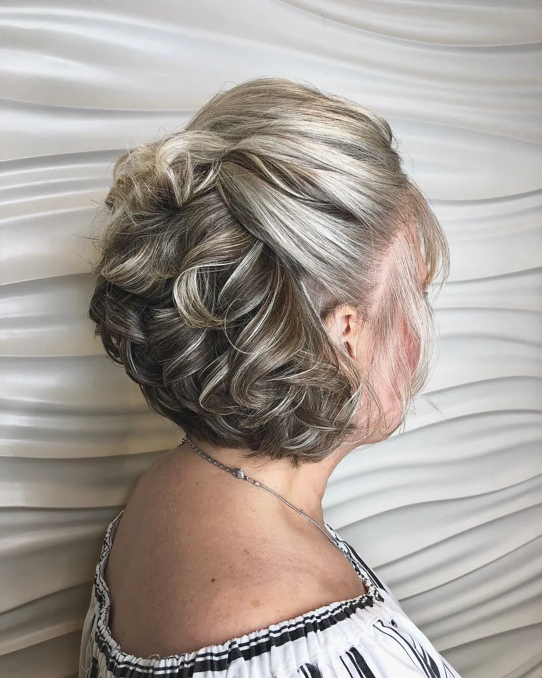 Curly textured updo with overlapping pinned sections for short hair