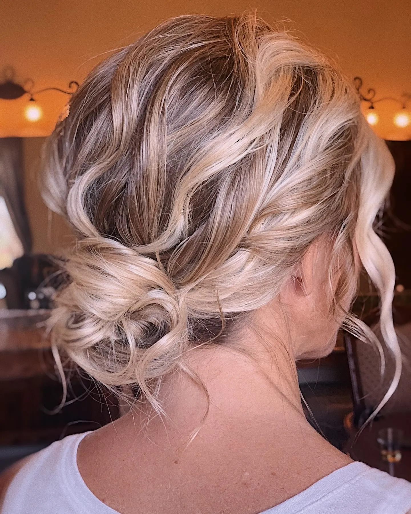 Loose low twisted updo with curled face-framing pieces