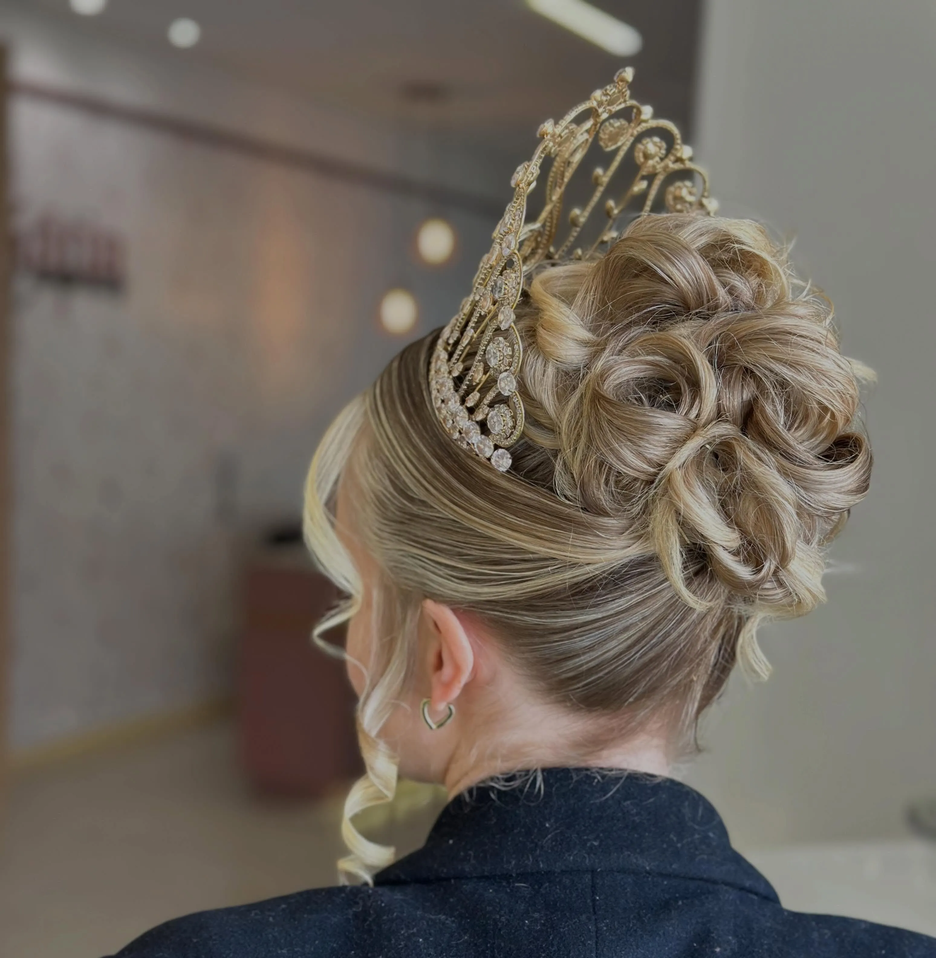 Intricate blonde curled updo with a gold crown