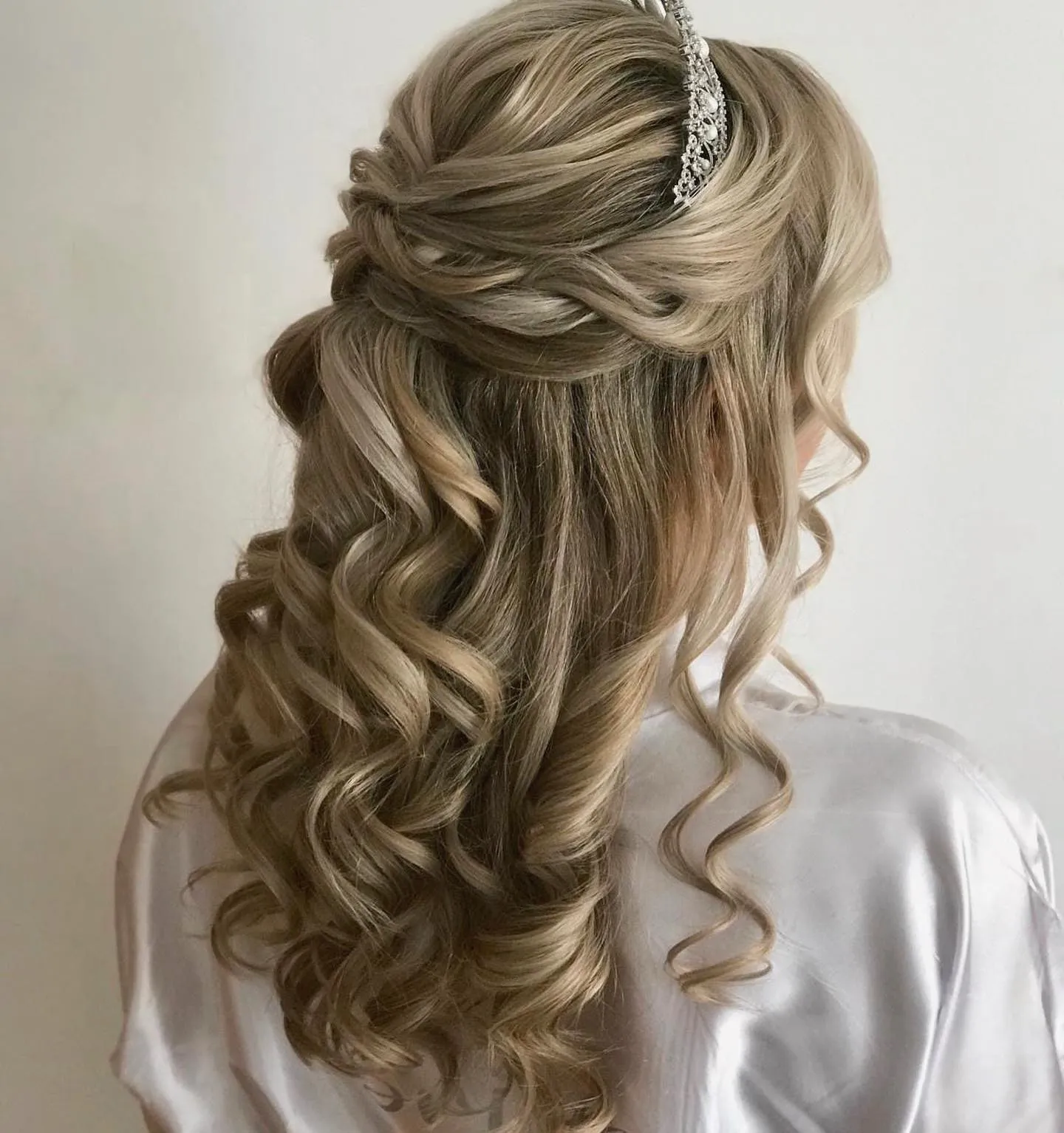 Curled half-up hairstyle with a slim silver crown