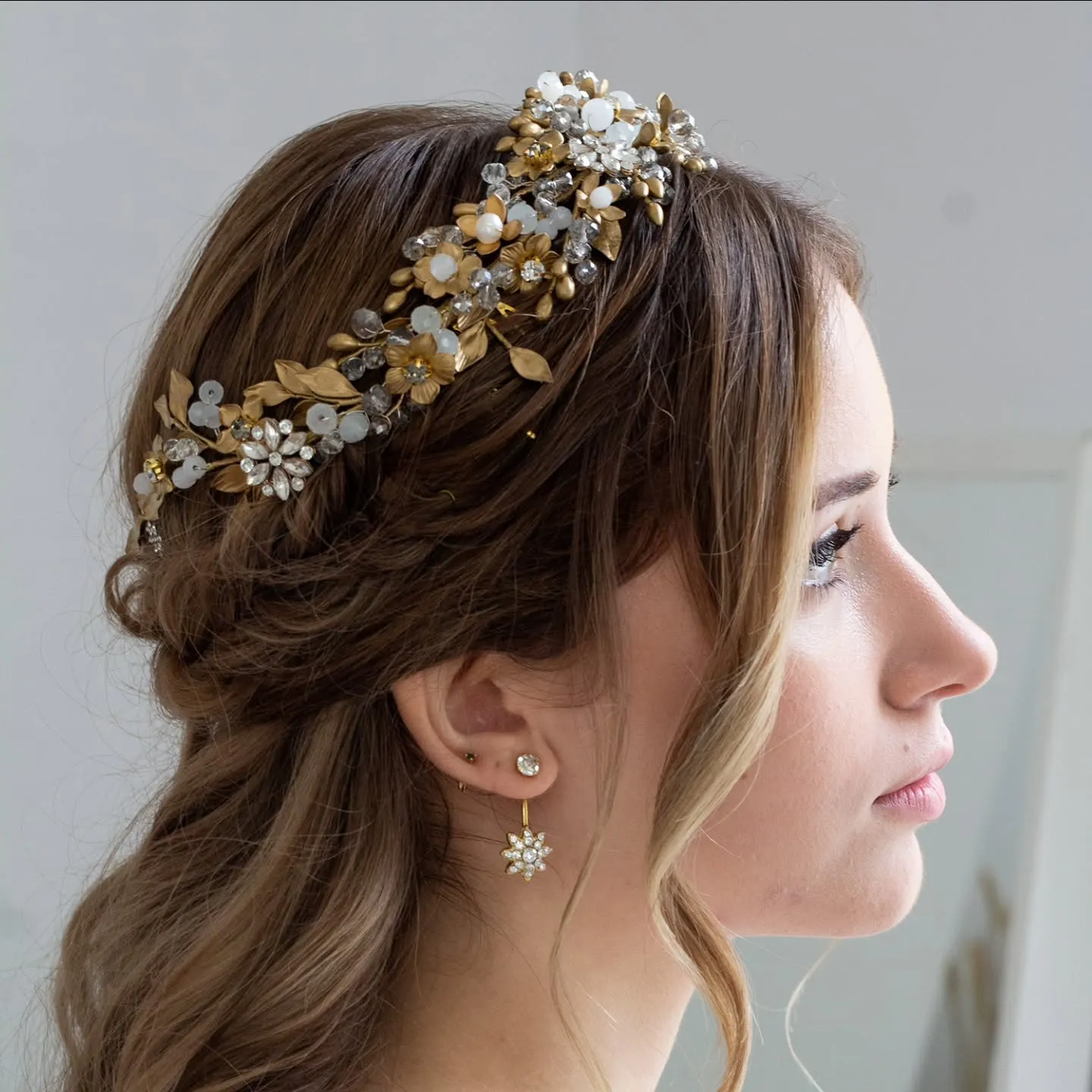 Twisted half-up wedding hair with a gold and crystal floral crown