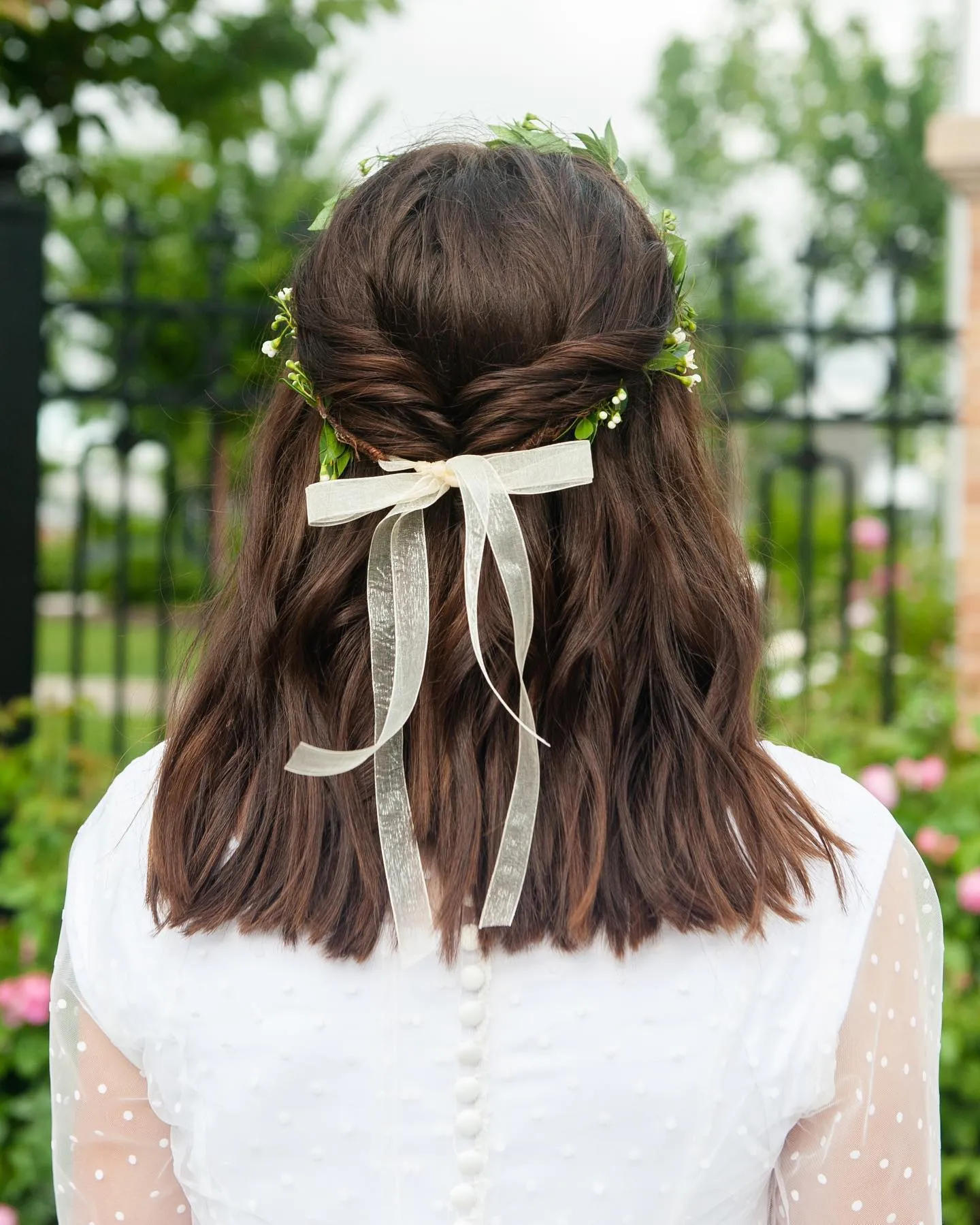 Shoulder-length half-up wedding hair with greenery and an ivory ribbon
