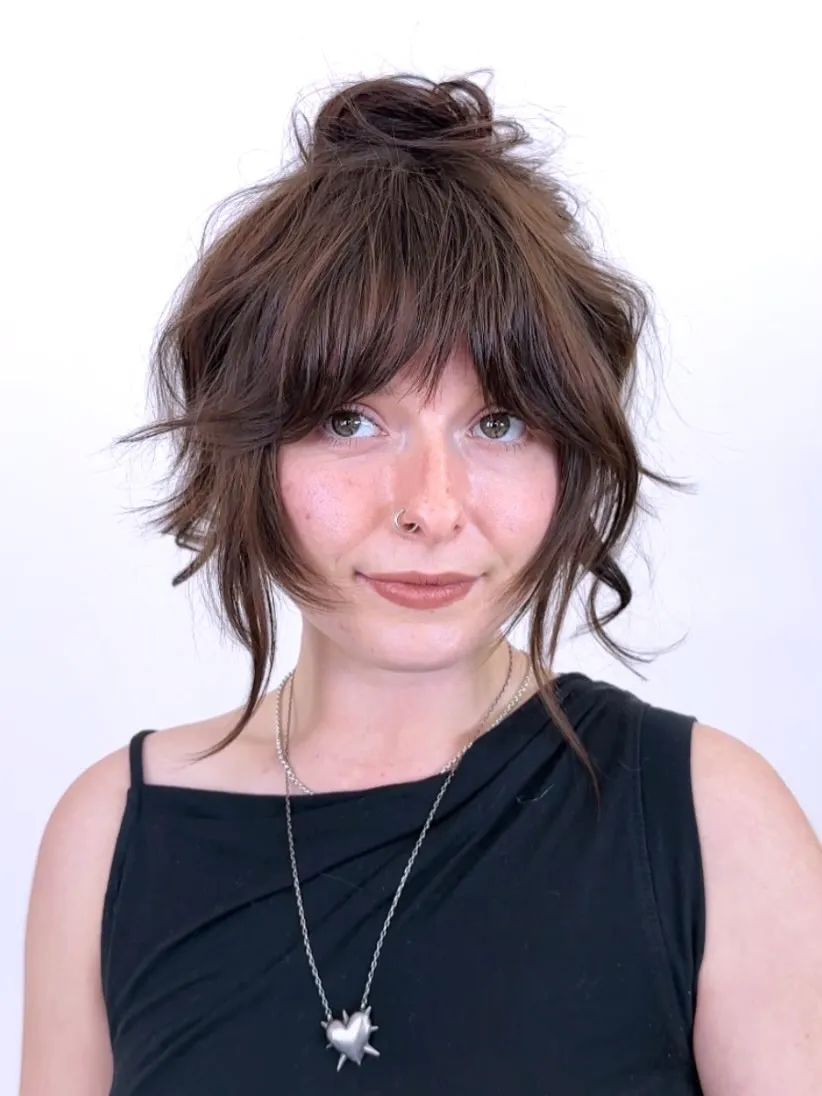 Loose dark top bun with curtain fringe and long curled side pieces