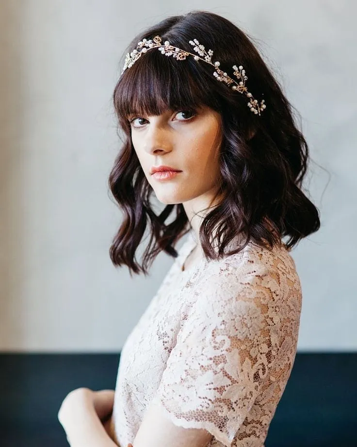 Wavy dark bridal bob with a full fringe and delicate floral crown