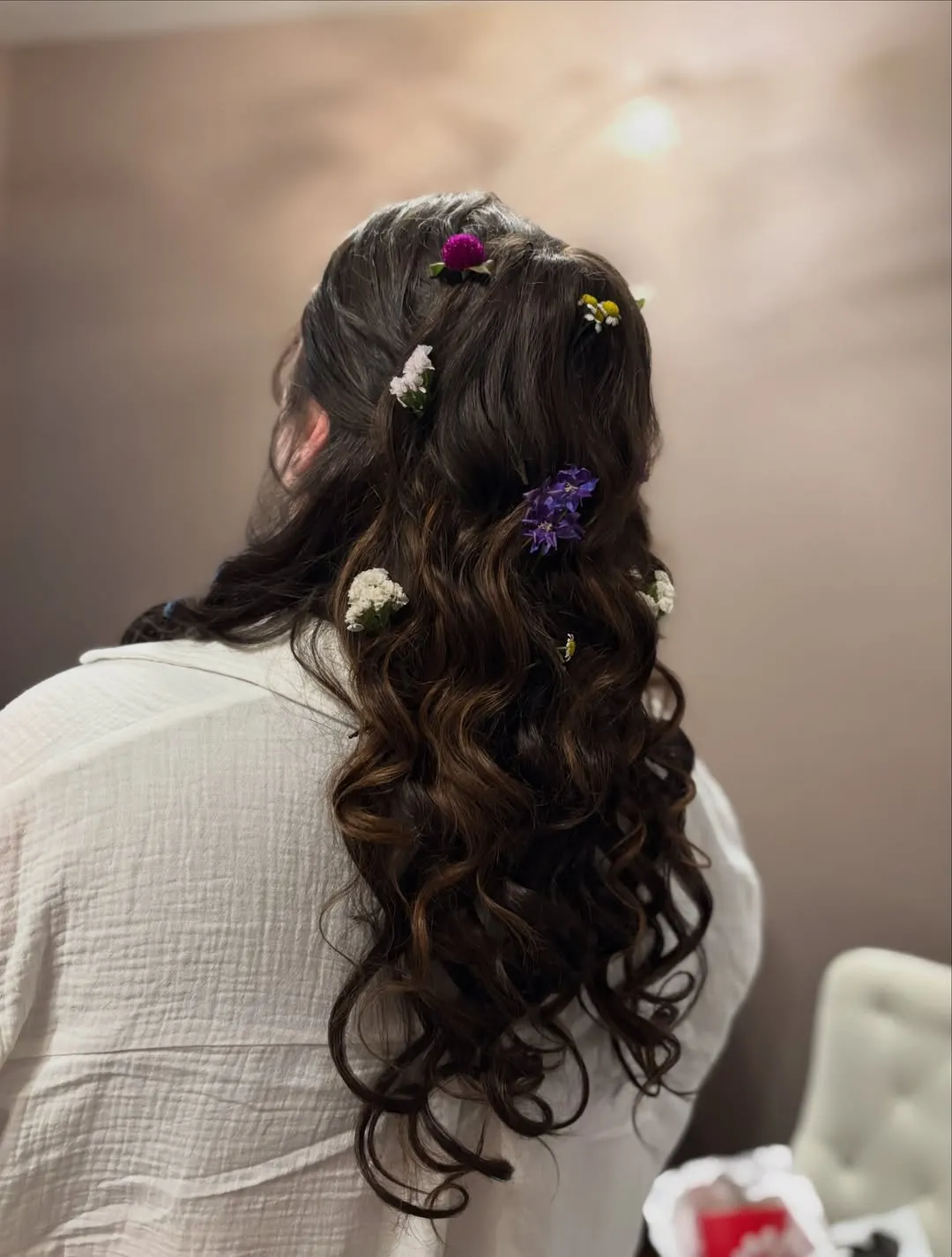 Dark half-up bridal curls with scattered wildflowers