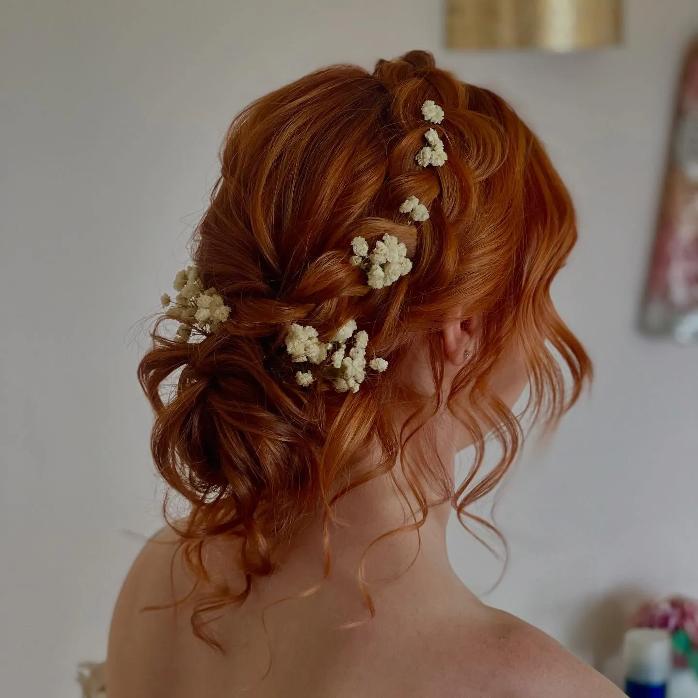Loose low bridal bun with baby's breath and curled tendrils