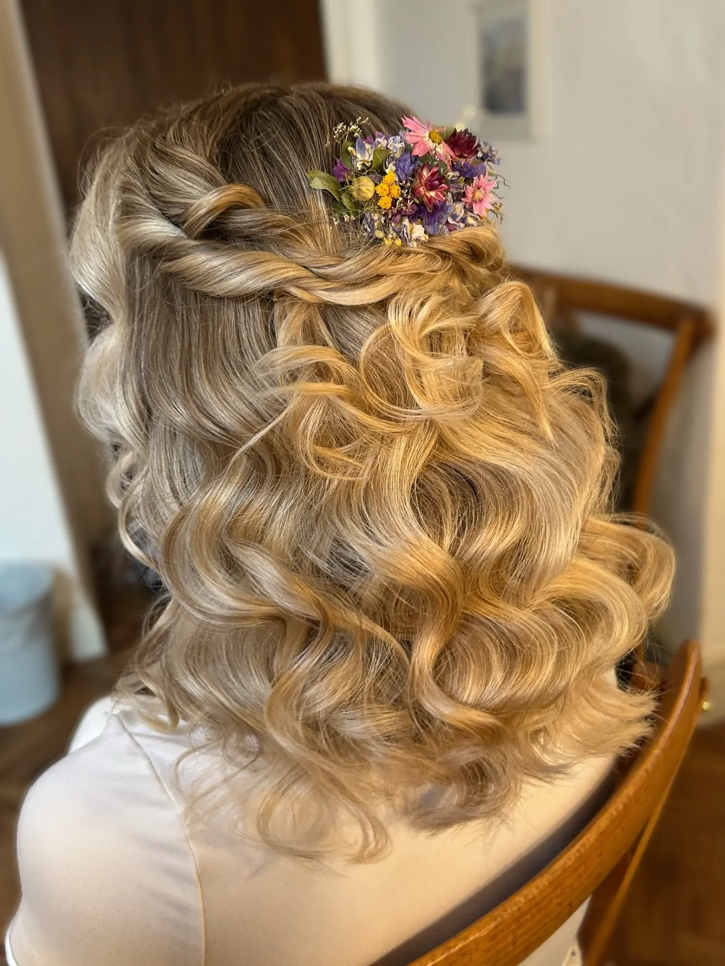 Half-up twisted bridal hairstyle with wildflowers and brushed curls