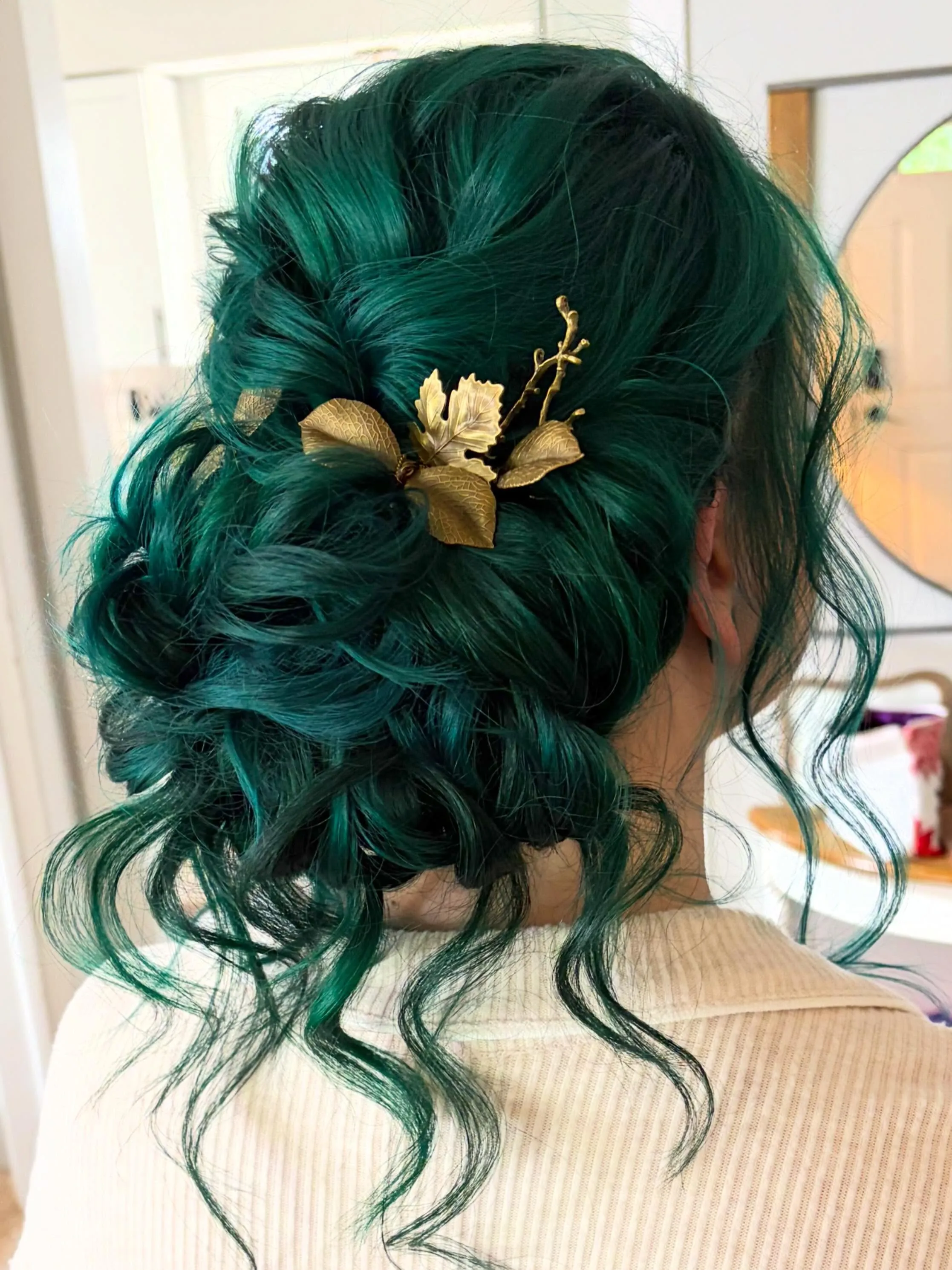 Textured low bridal updo with a gold floral comb